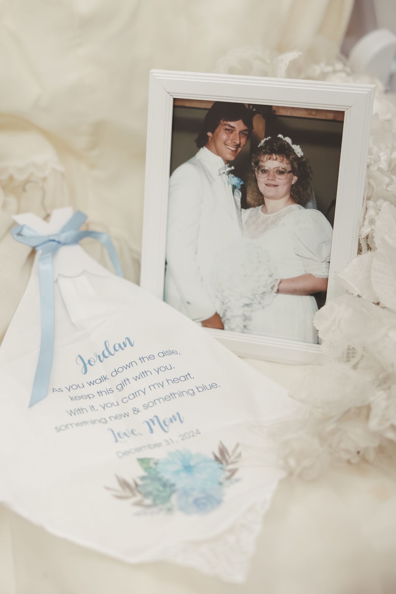 A vintage wedding photo displayed with a light blue wedding invitation on white fabric.