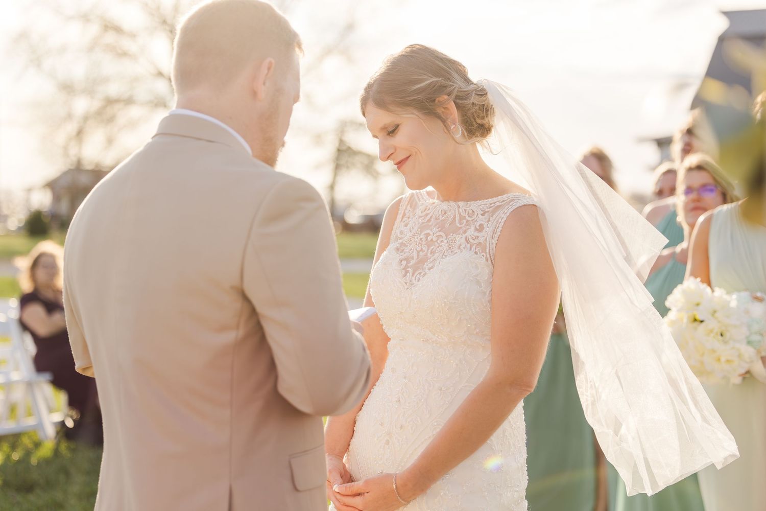 An outdoor wedding ceremony scene during golden hour with couple exchanging vows.