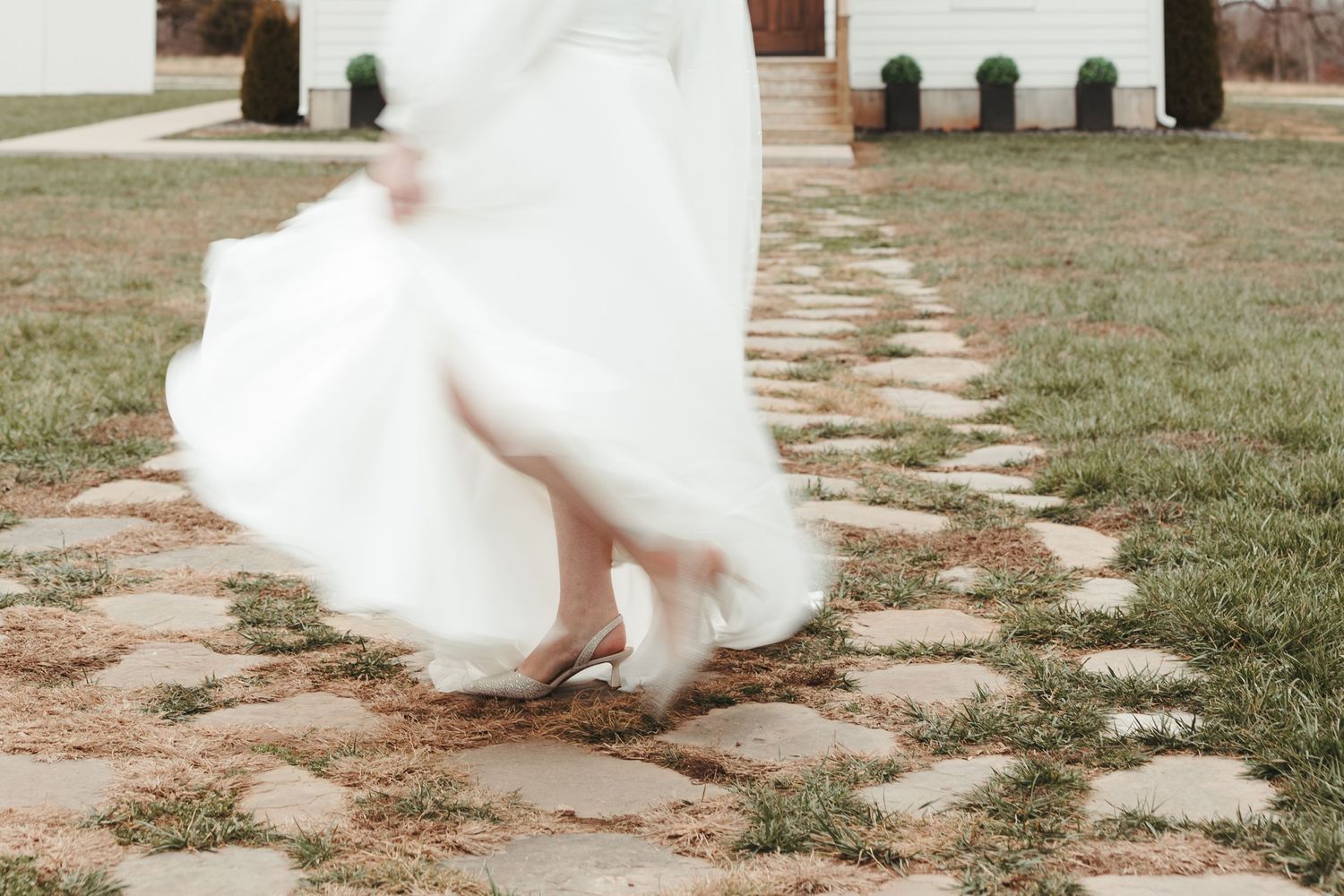 Flowing white wedding dress swirls on a stone pathway in motion shot.