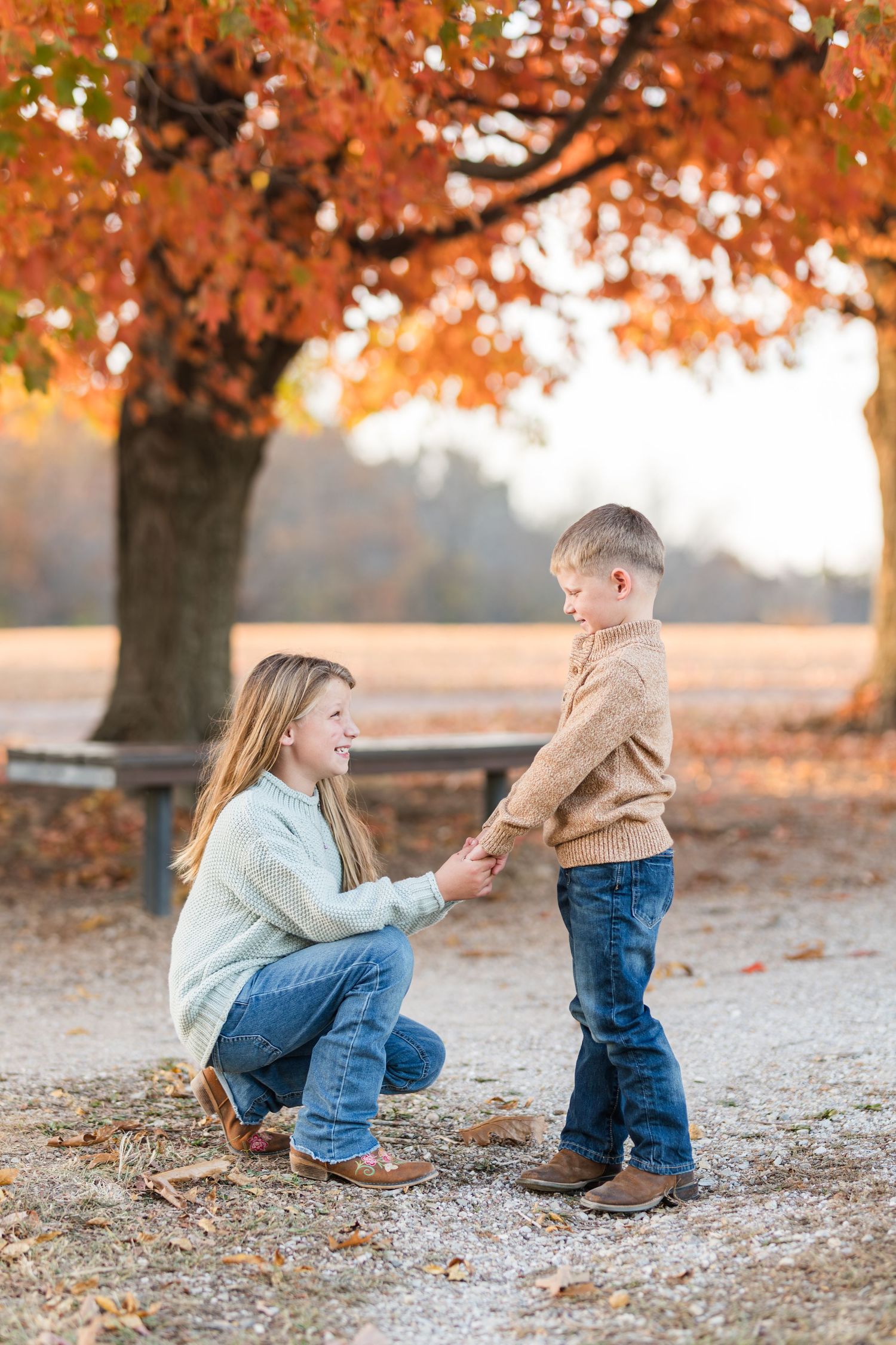 Touching autumn scene with parent and child holding hands under vibrant orange fall foliage.