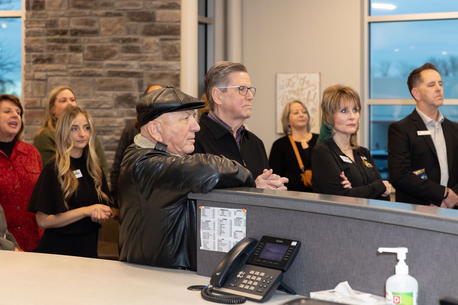 Staff members watching a presentation at a curved reception desk with stone wall backdrop.