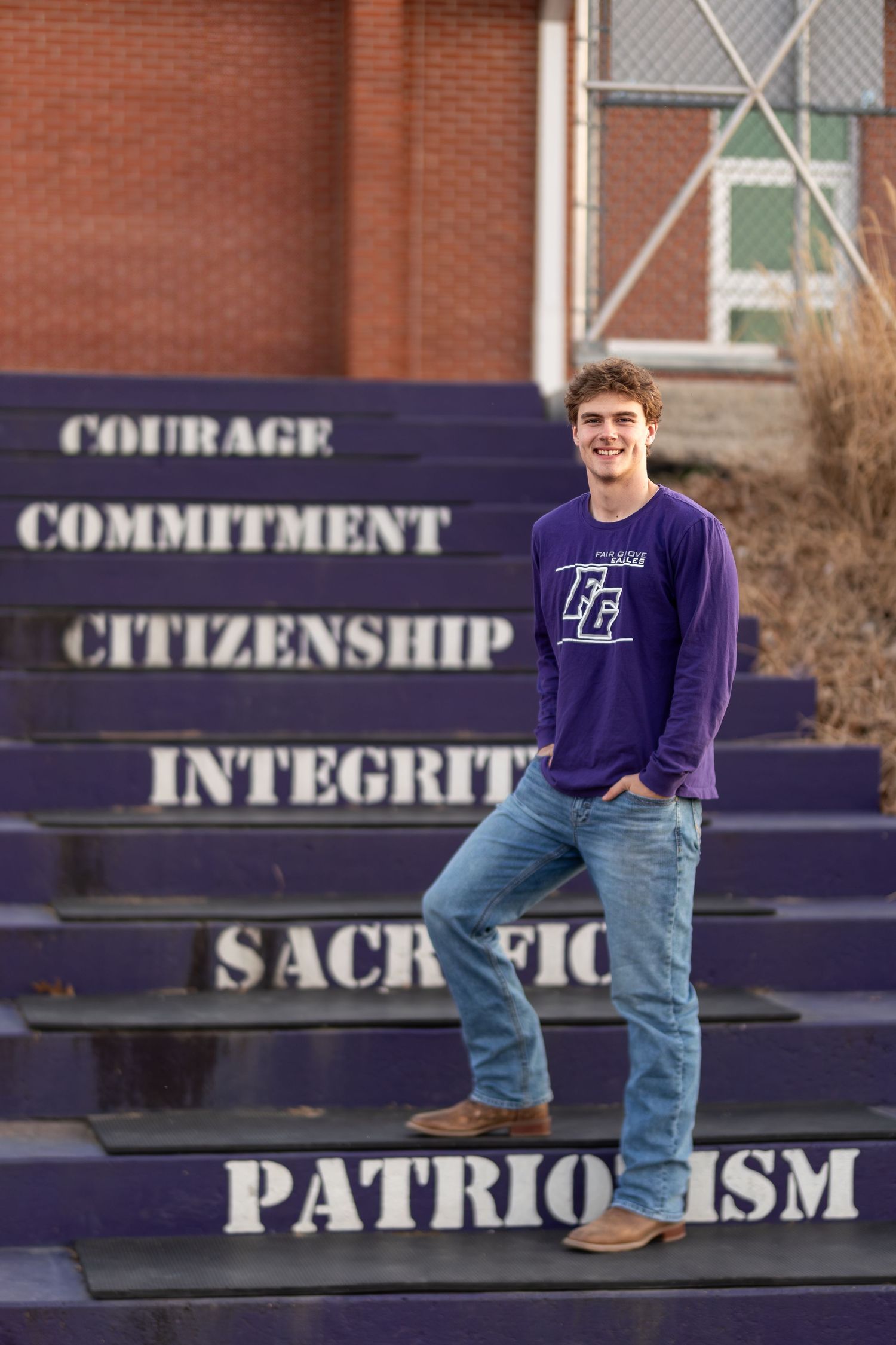 A student poses on purple painted school steps with inspirational words like Courage and Integrity.