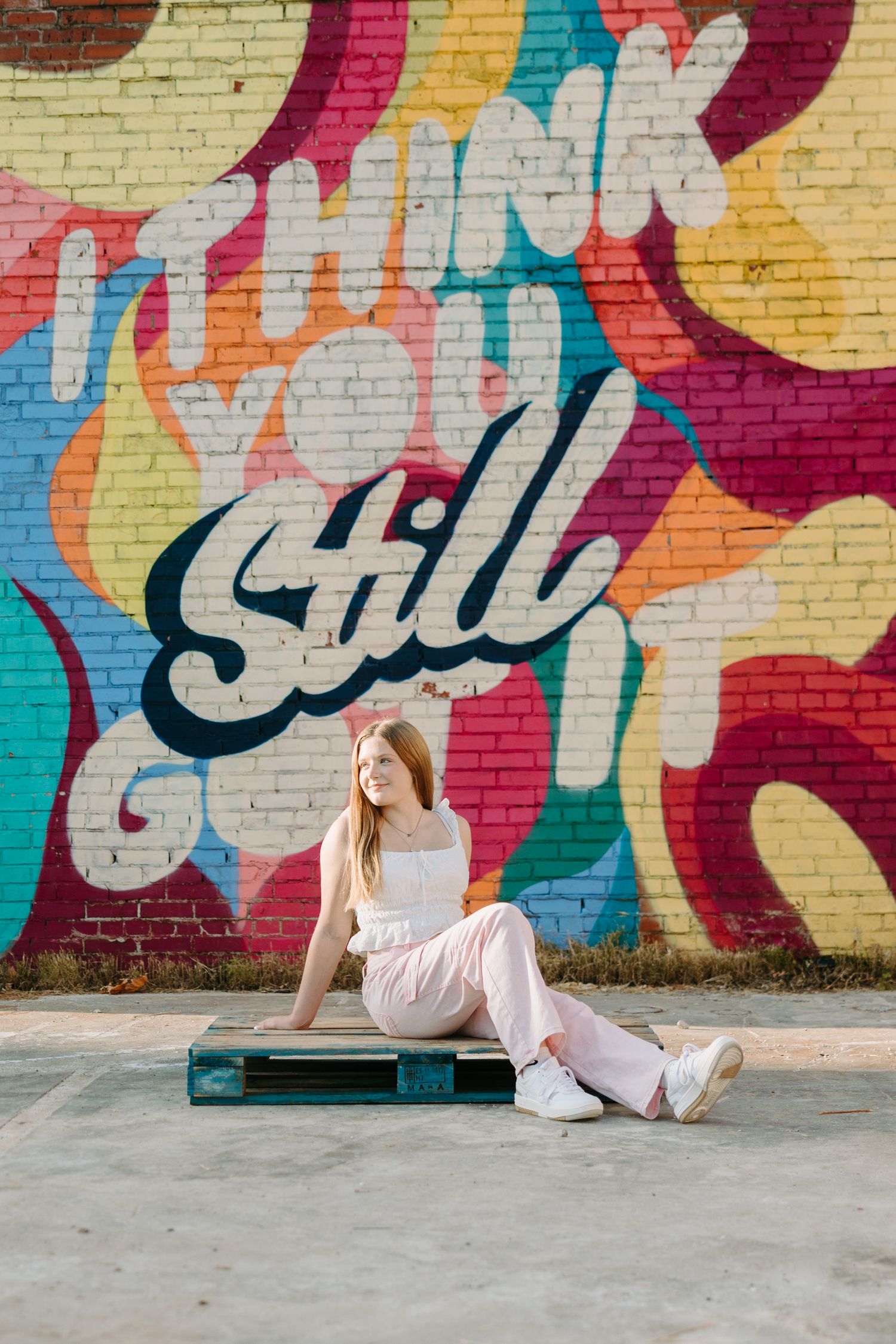 A colorful graffiti mural serves as a vibrant backdrop for outdoor portraits against a brick wall.