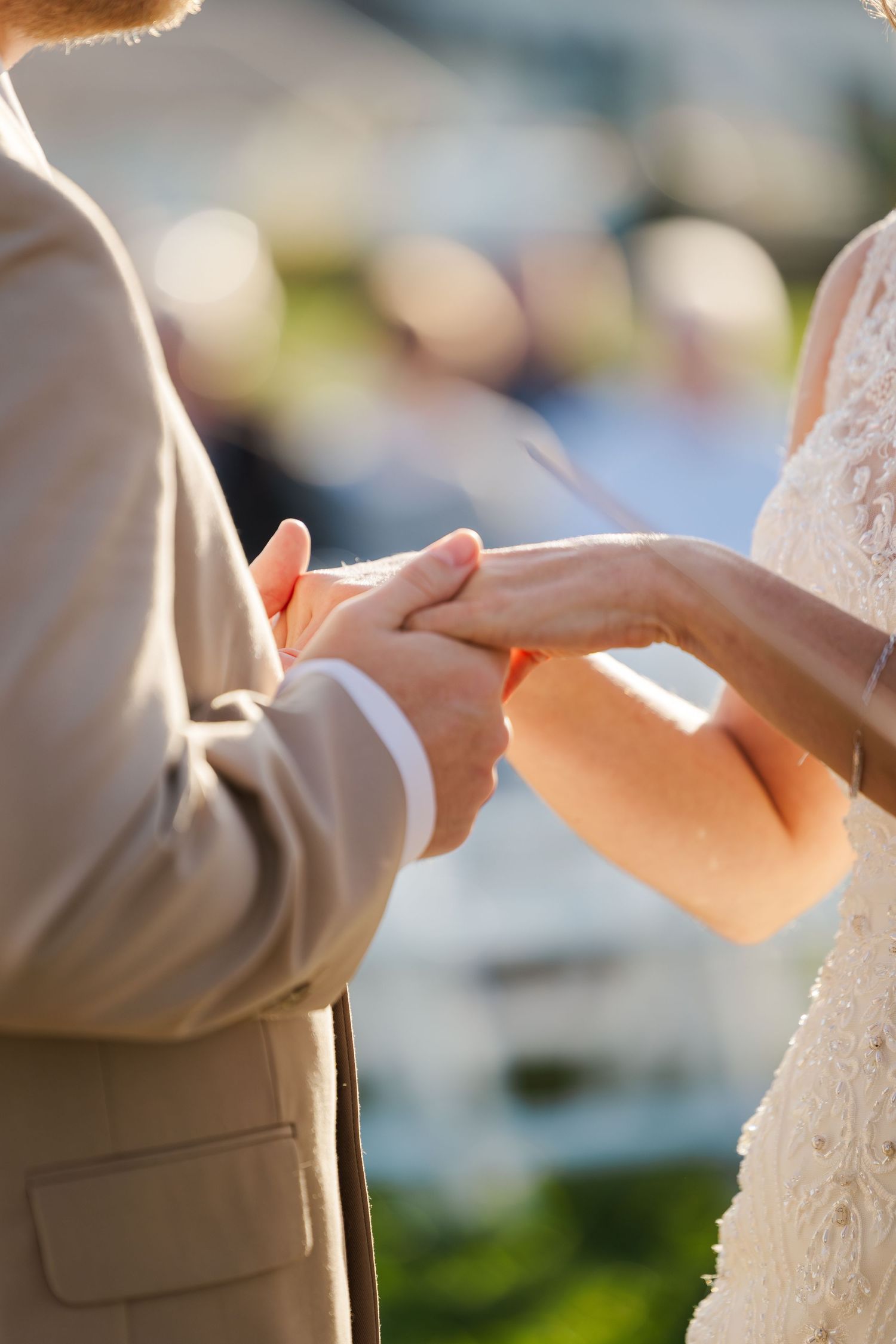 Close-up of hands exchanging rings during an outdoor wedding ceremony.