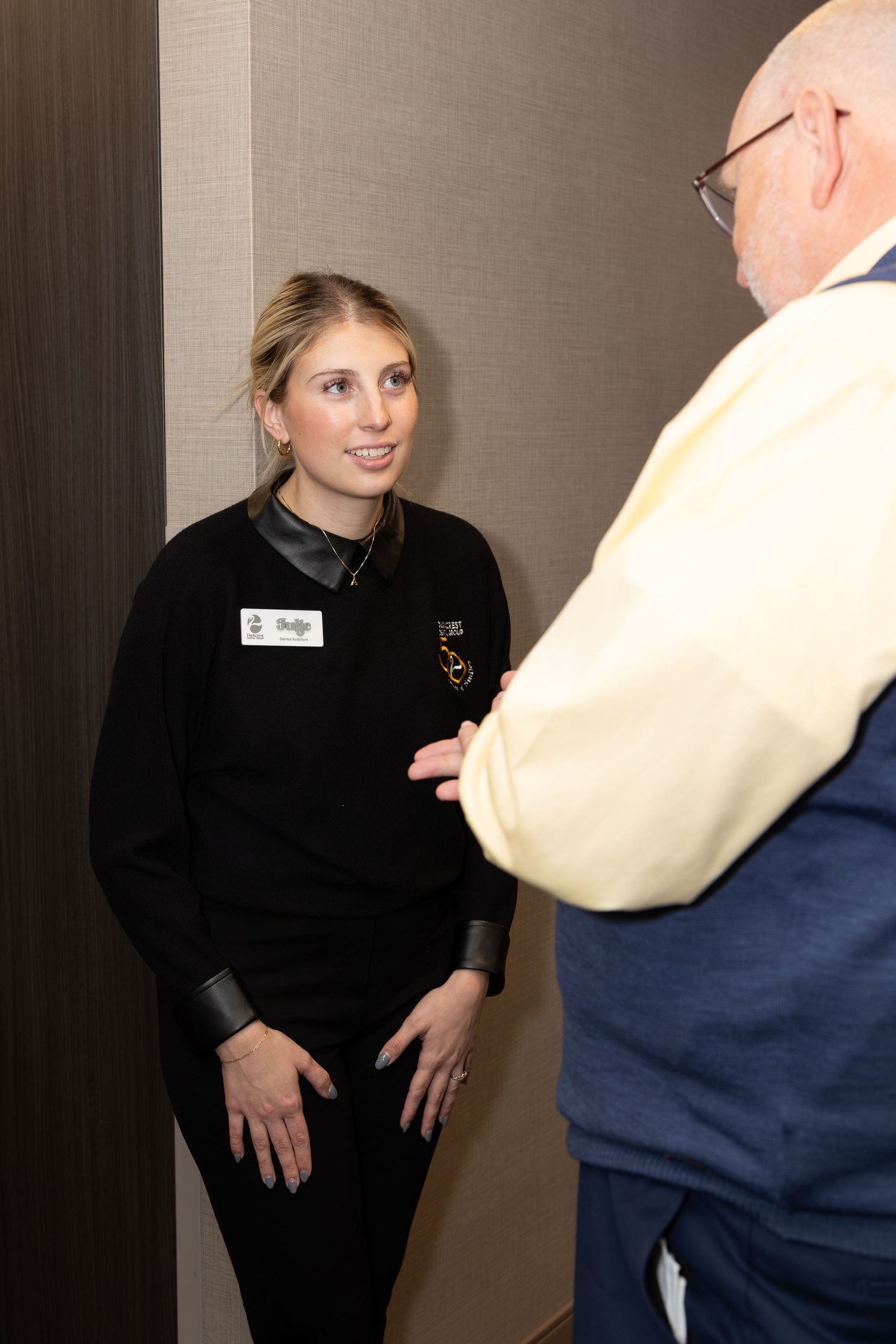 Professional staff member in black uniform having a conversation in an office hallway.