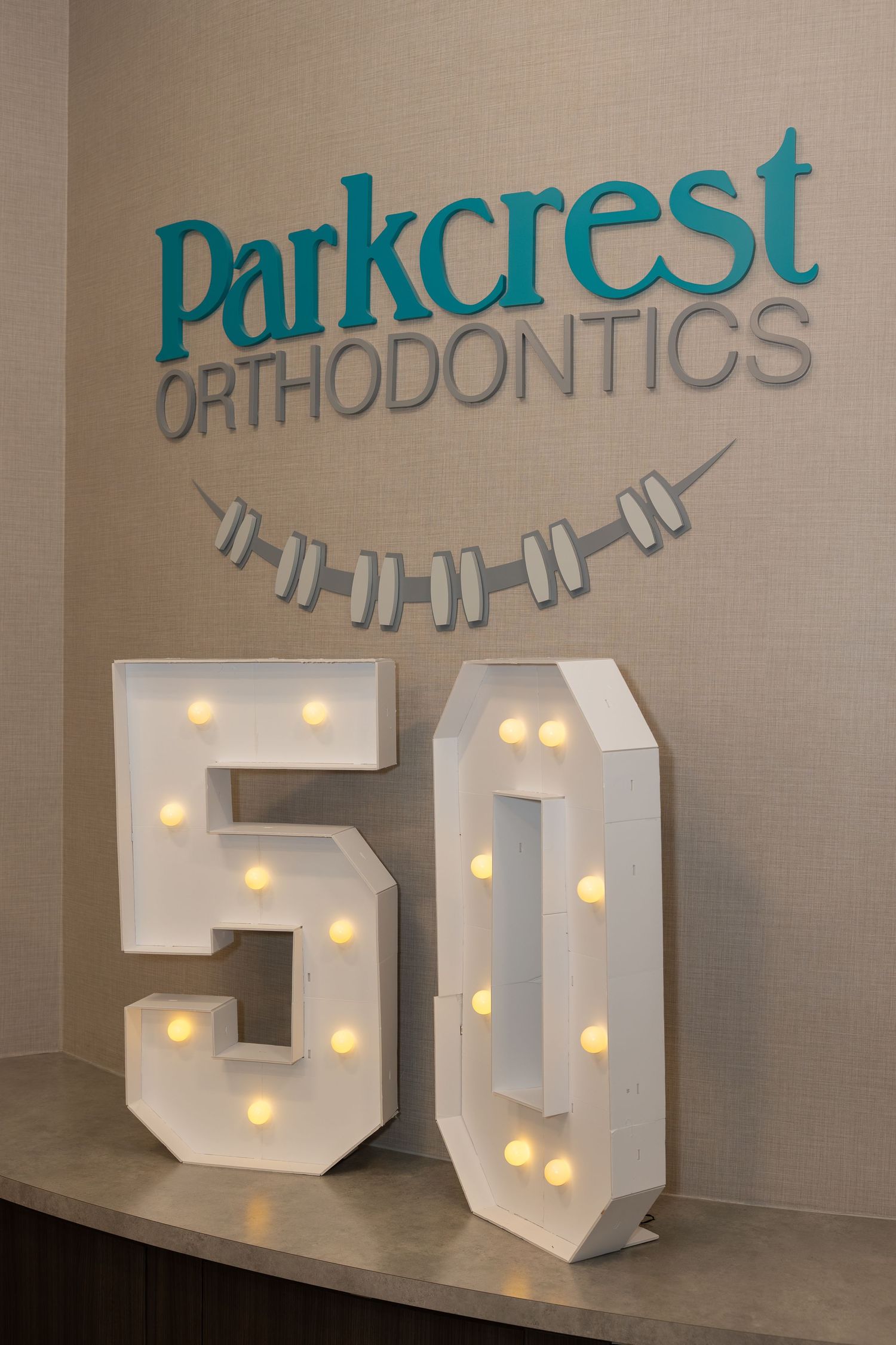 Illuminated number 50 display under Parkcrest Orthodontics logo with braces design.