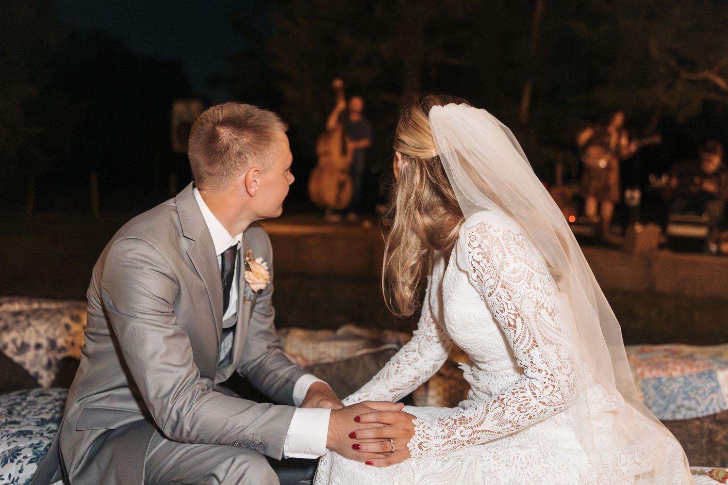 Intimate moment between newlyweds seated together in formal wedding attire at dusk.