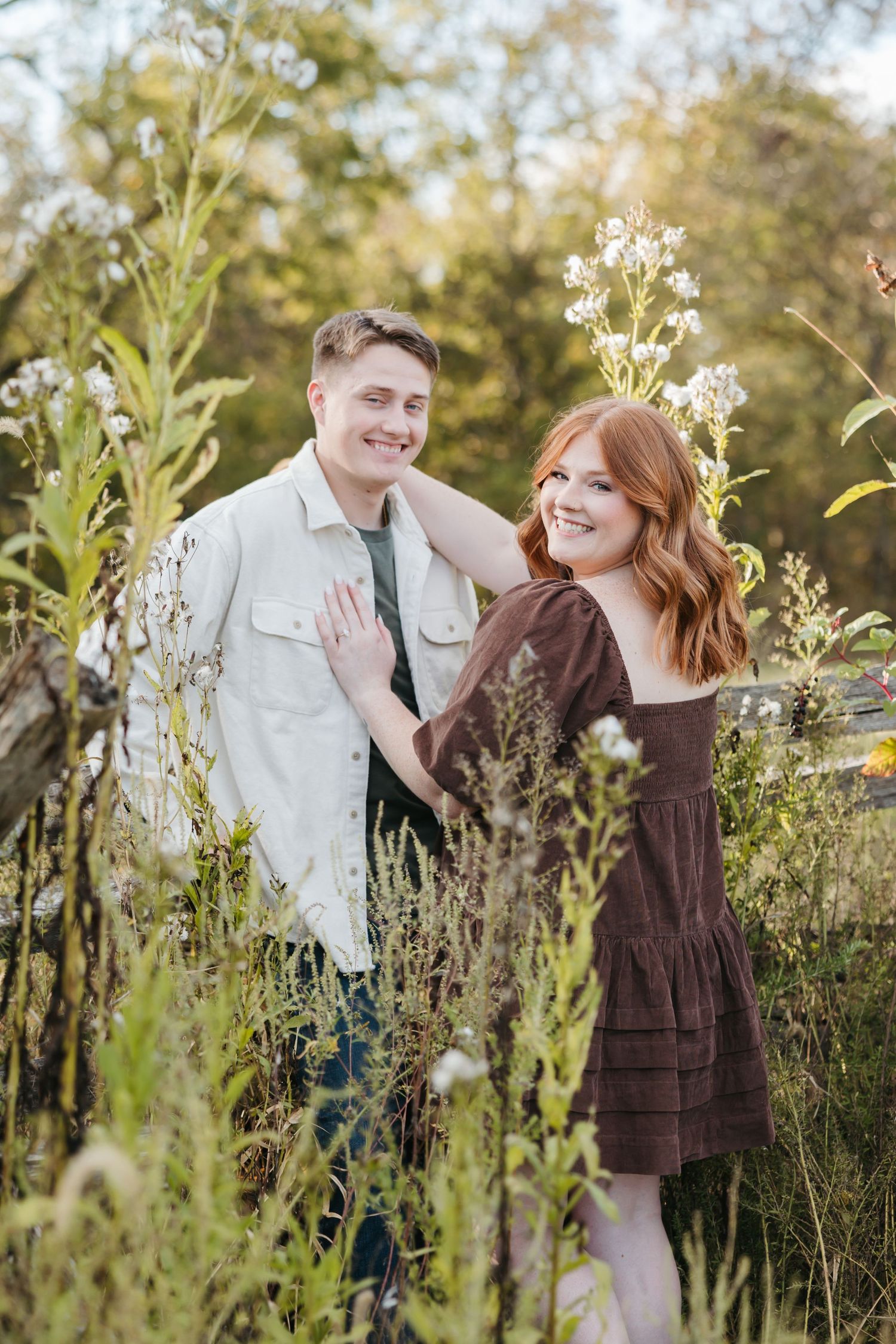 Joyful couple sharing tender moment surrounded by flowering plants in natural setting.