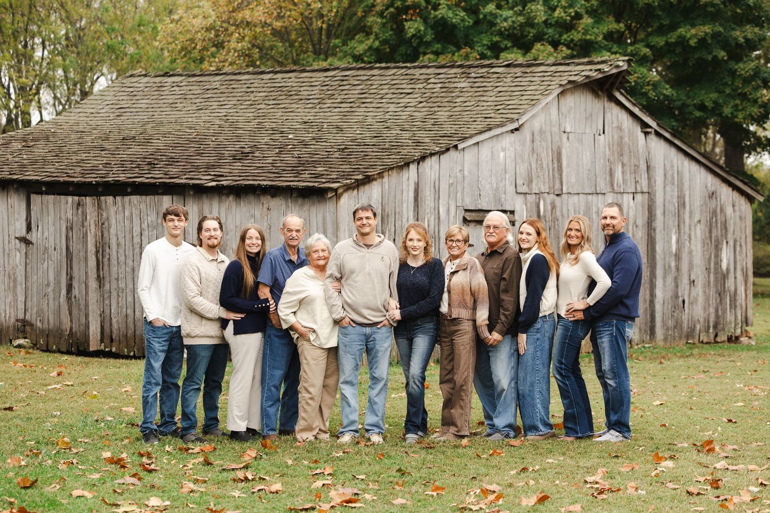 Family portrait series showing group poses against rustic barn backdrop in casual fall attire.