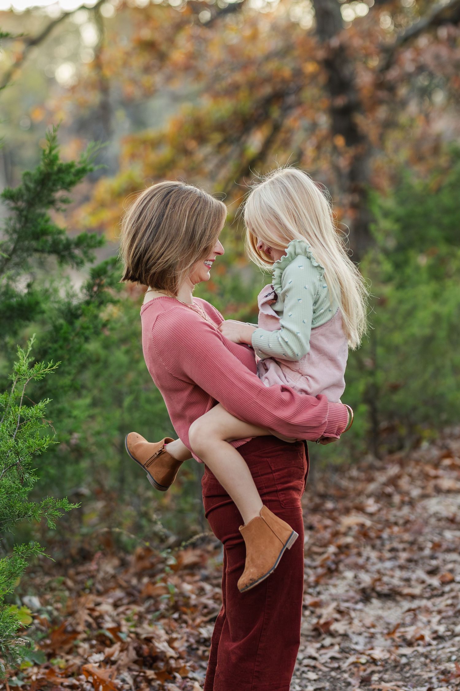 Mother and daughter sharing a tender moment on an autumn trail surrounded by fall foliage.