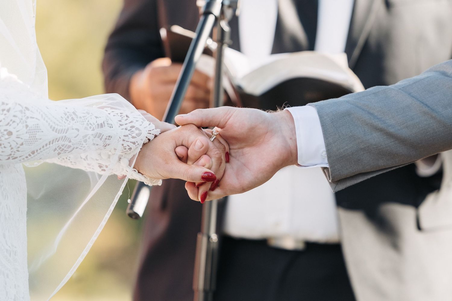 Close-up of wedding rings being exchanged during an outdoor ceremony.