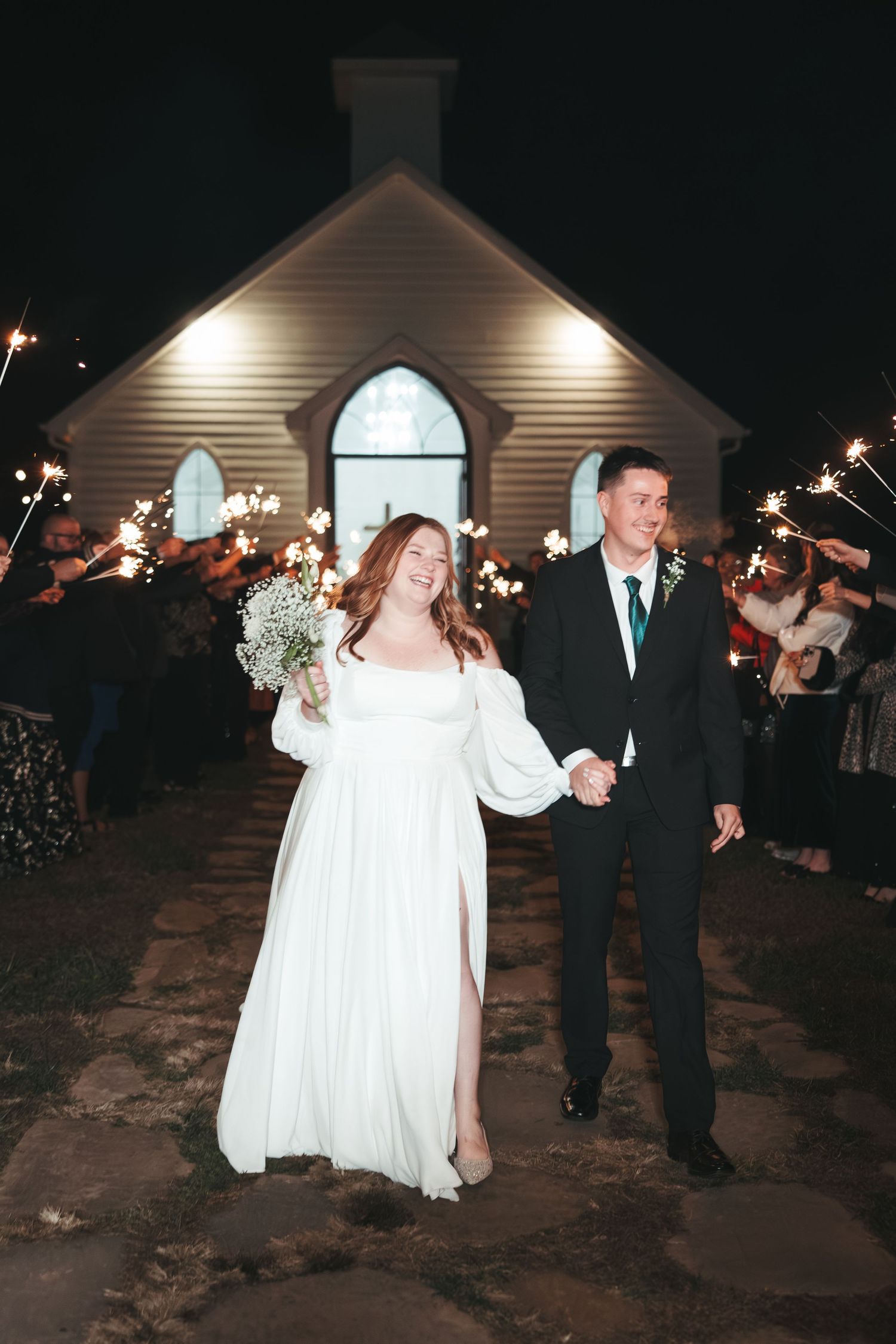 Romantic sparkler exit for newlyweds outside rustic chapel.
