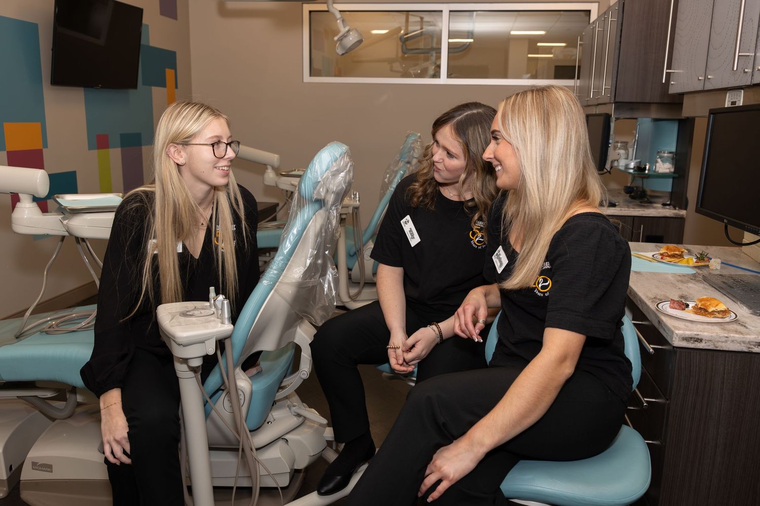 Dental staff members having a conversation in a modern dental office treatment room.