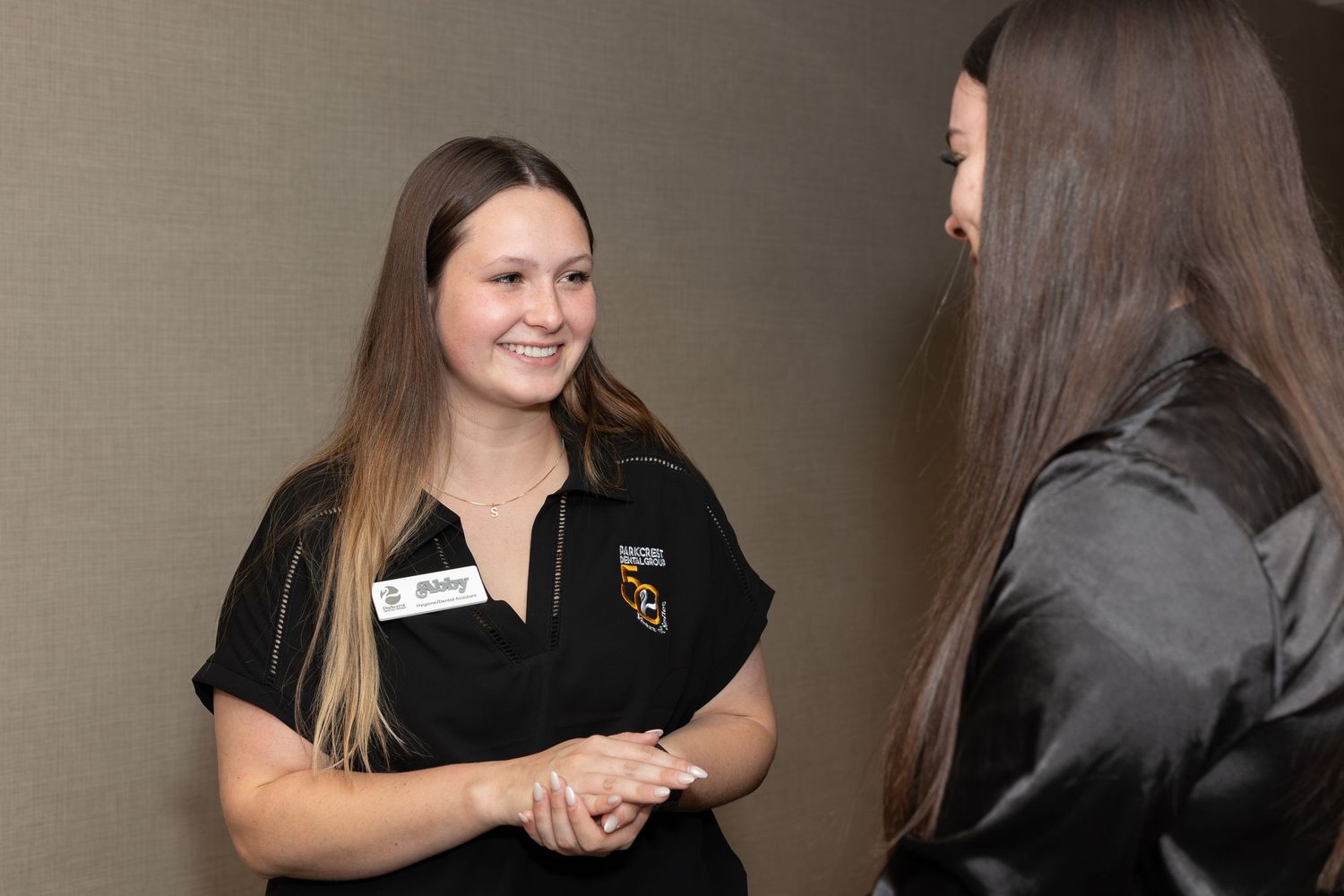 Staff members having a friendly interaction in a corporate hallway setting.