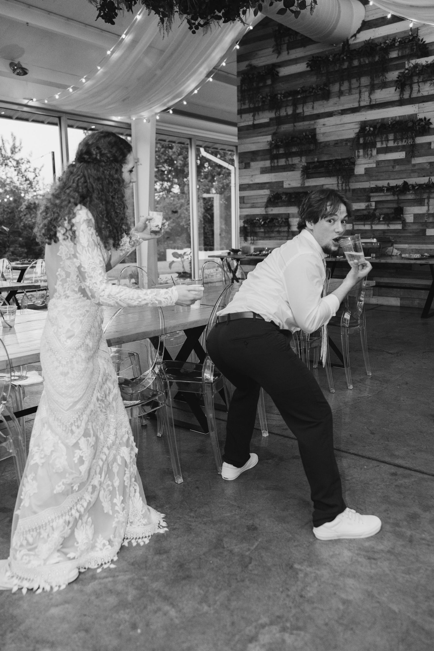 Bride and groom dancing joyfully at their wedding reception in black and white.