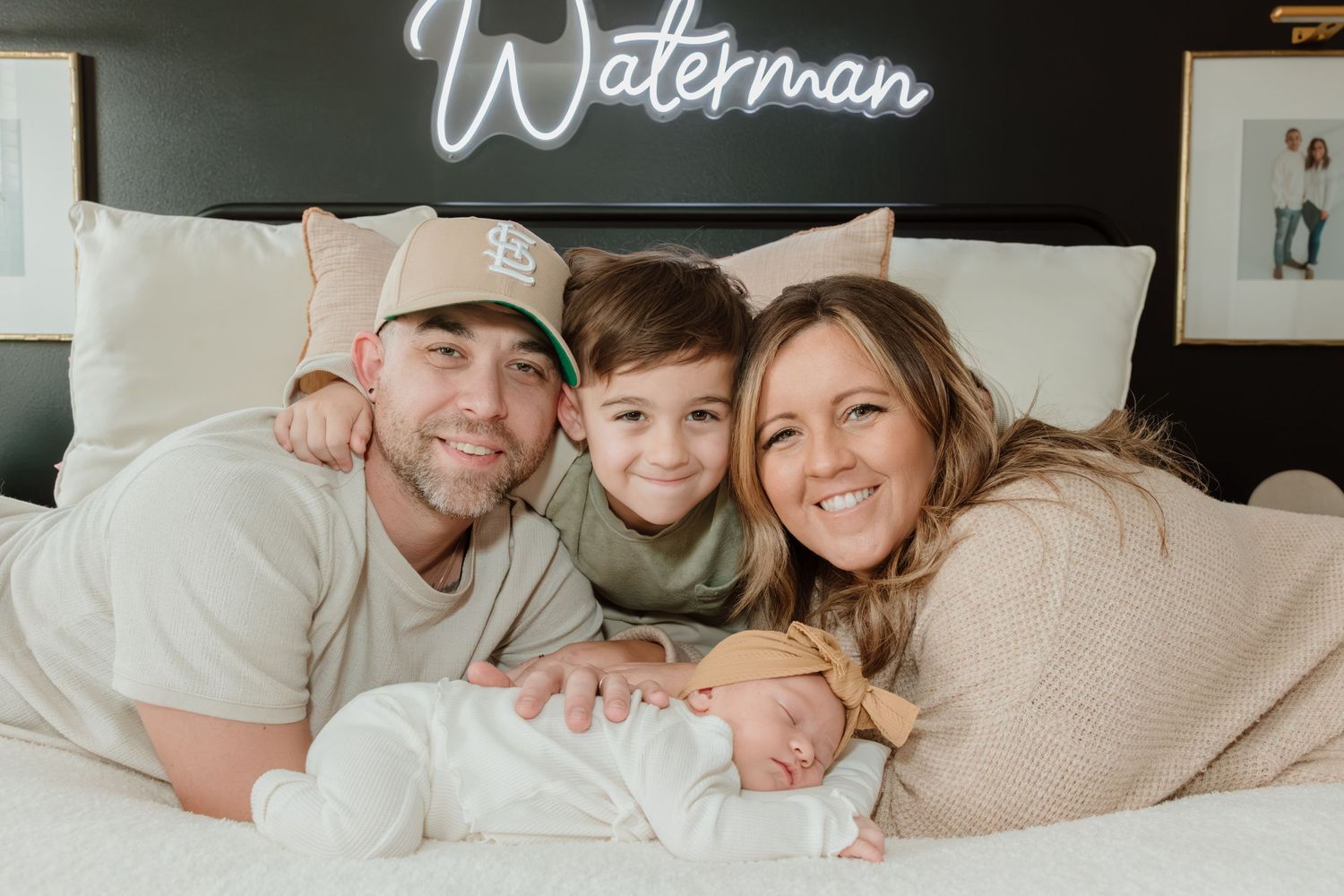 Family of four snuggling together on white bedding while relaxing at home.