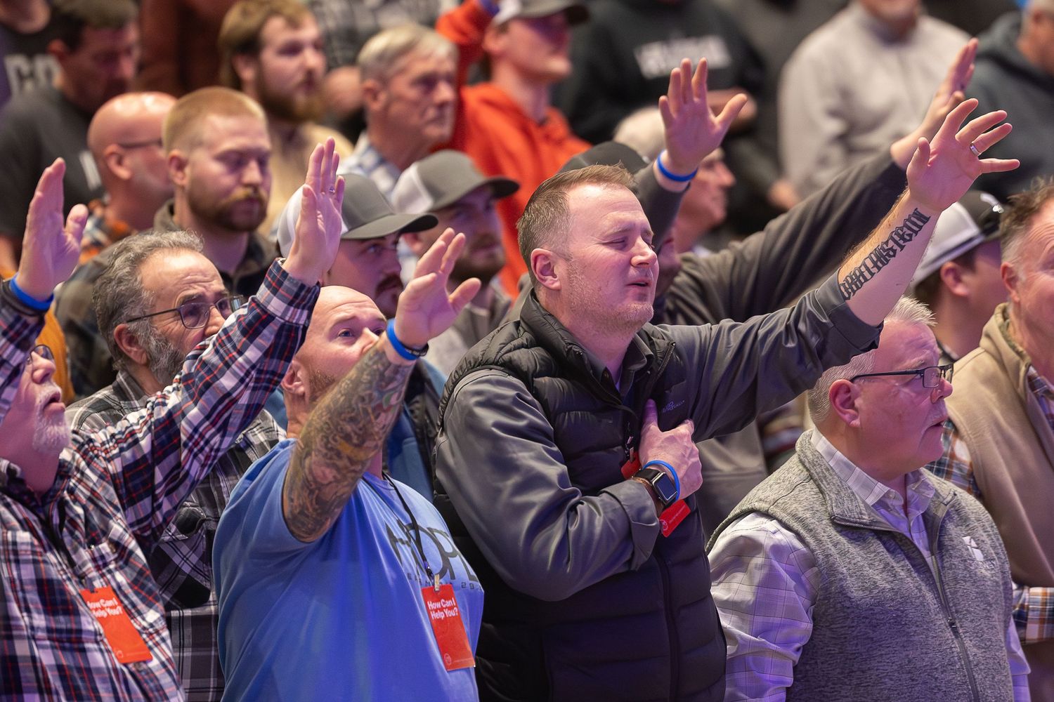 Enthusiastic crowd with raised hands cheering and celebrating at an indoor sporting event.
