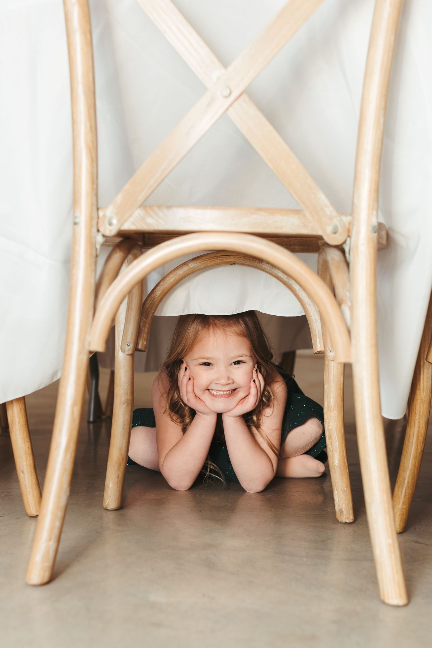 A wooden chair frame with someone playfully peeking through from underneath.