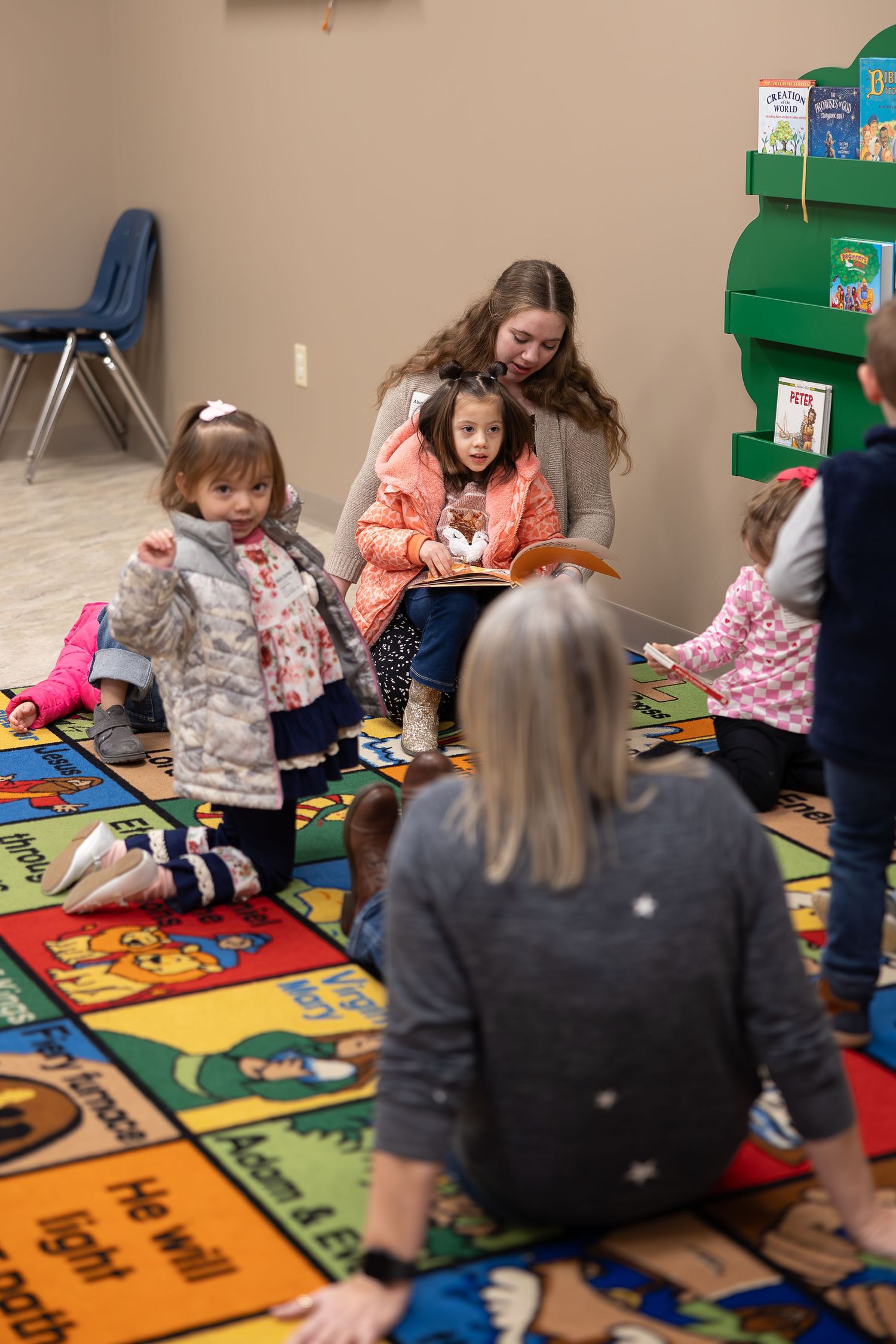 Group gathered on colorful educational carpet for indoor learning activities.