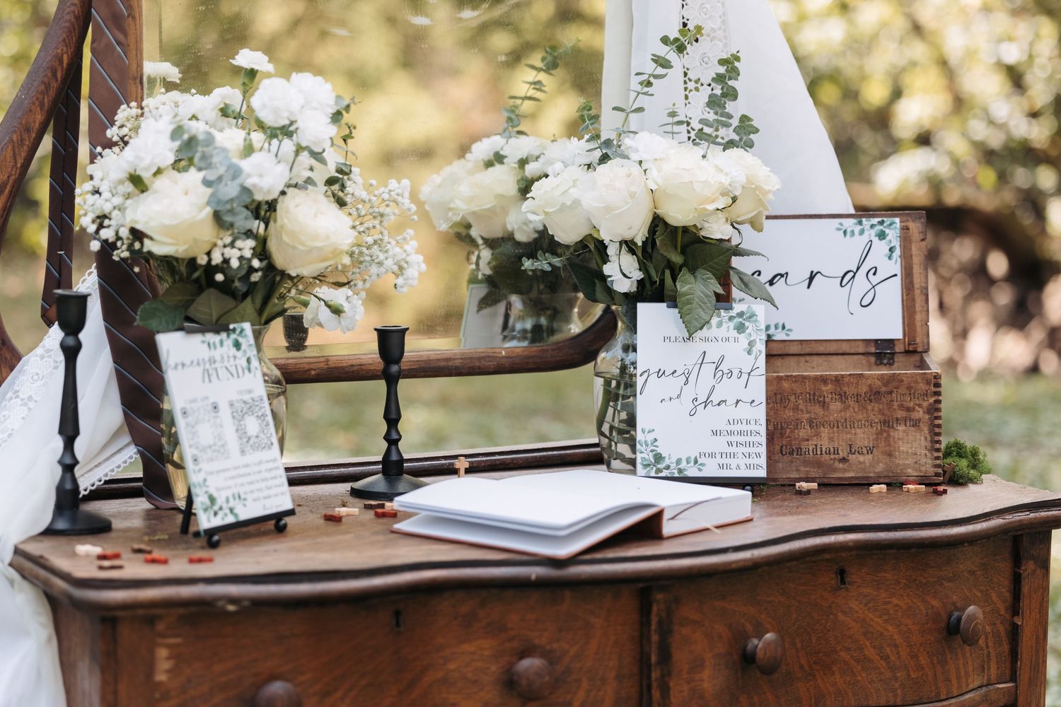 Vintage wooden dresser decorated with white floral arrangements and wedding signage.