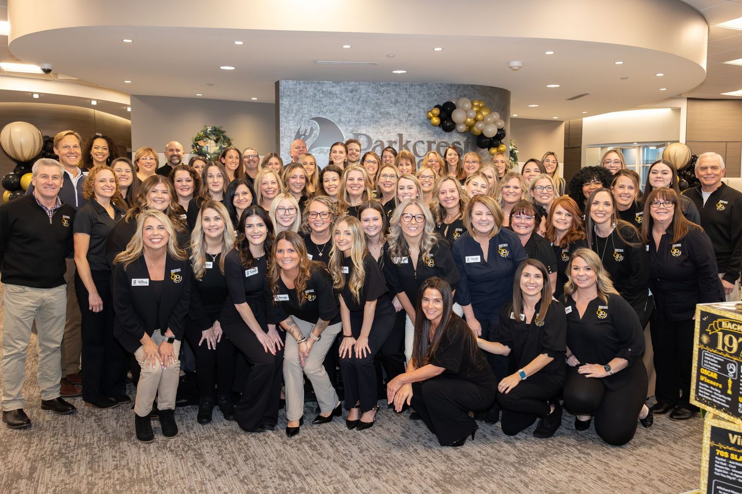 Large group photo of team members wearing coordinated black and navy business attire.