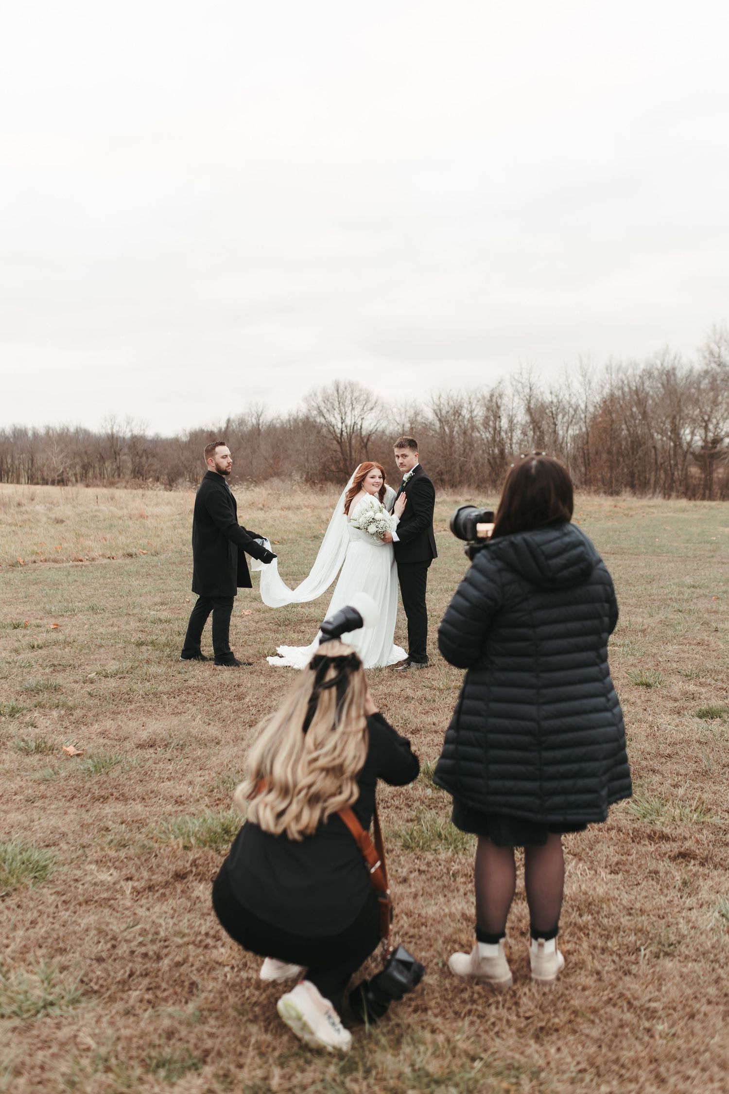 Behind-the-scenes view of photographers capturing a winter wedding ceremony.