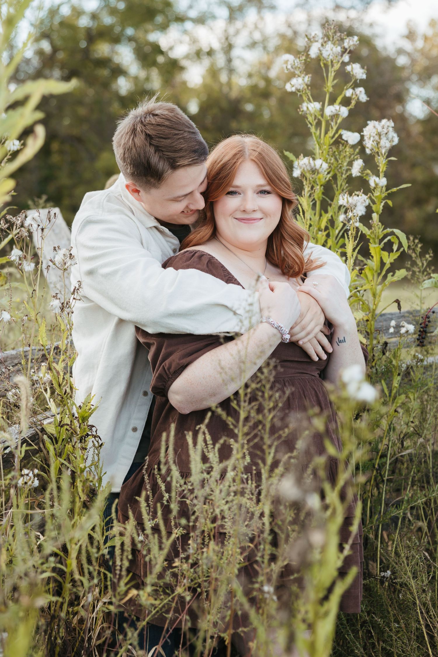 Sweet candid moment between a couple surrounded by white wildflowers in a natural setting.