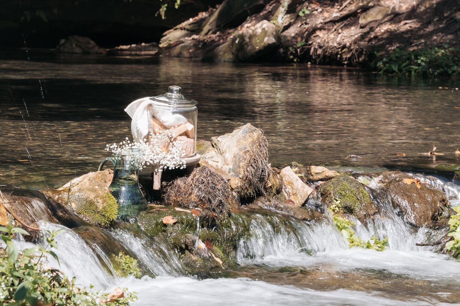 Peaceful stream with mossy rocks and flowing water in a natural setting.
