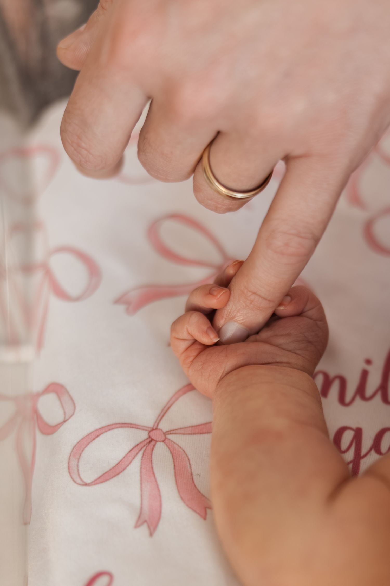 Hand tracing pink decorative bow designs on white fabric with fingers, creating delicate patterns.