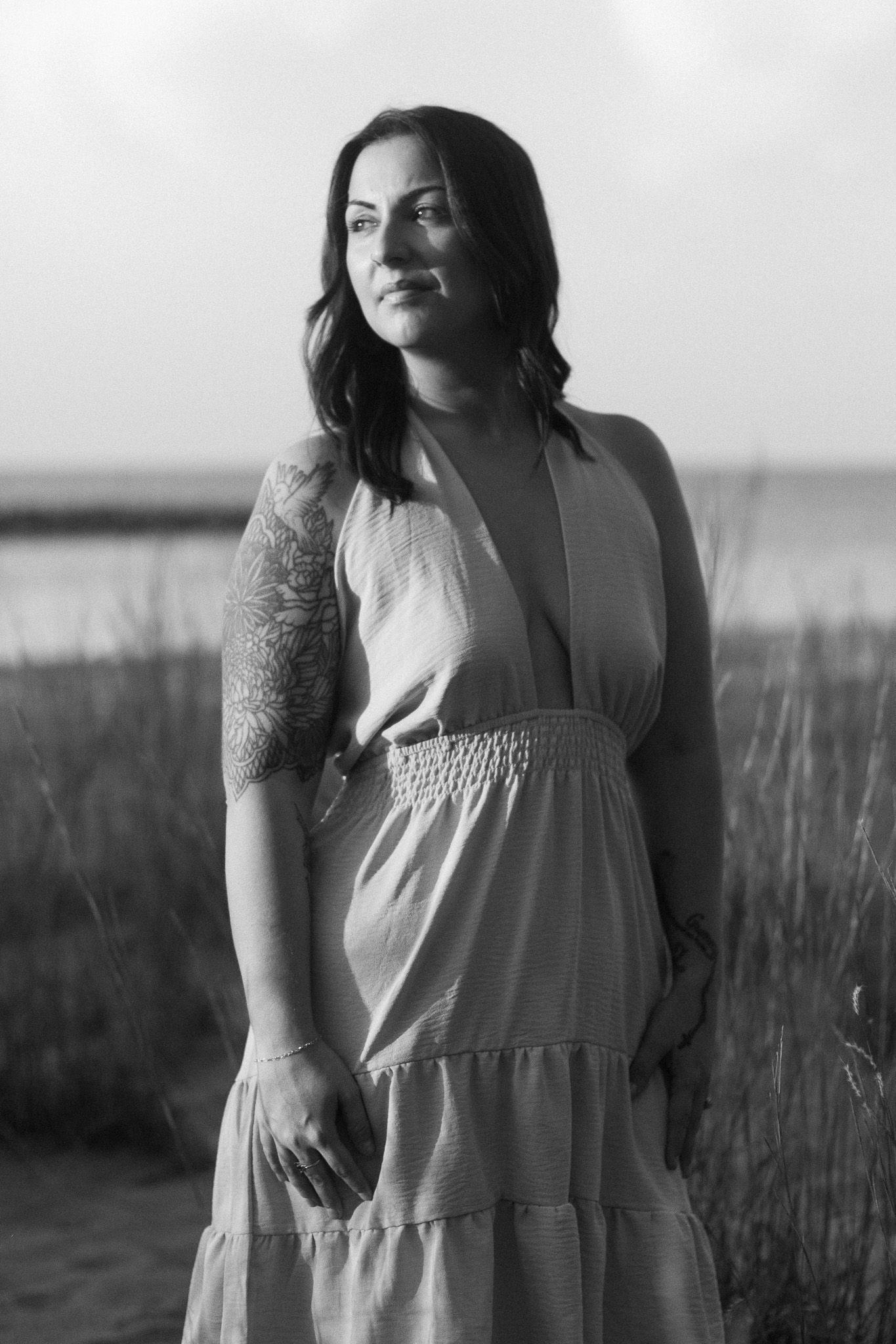 A black and white image of a woman who stands empowered looking into the sunset