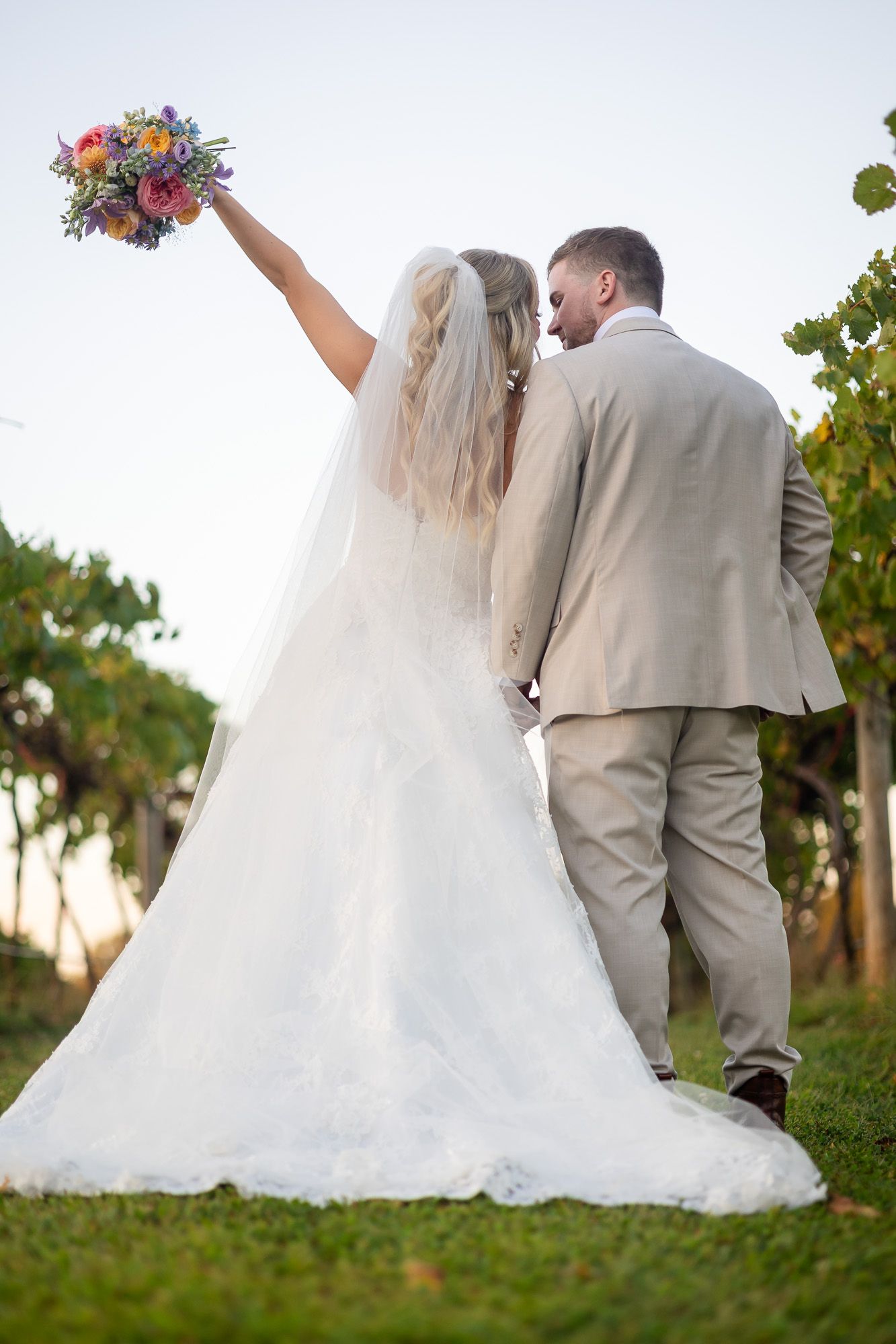 A bride and groom walking together through a sunlit vineyard during their wedding photo session in Ellijay Georgia