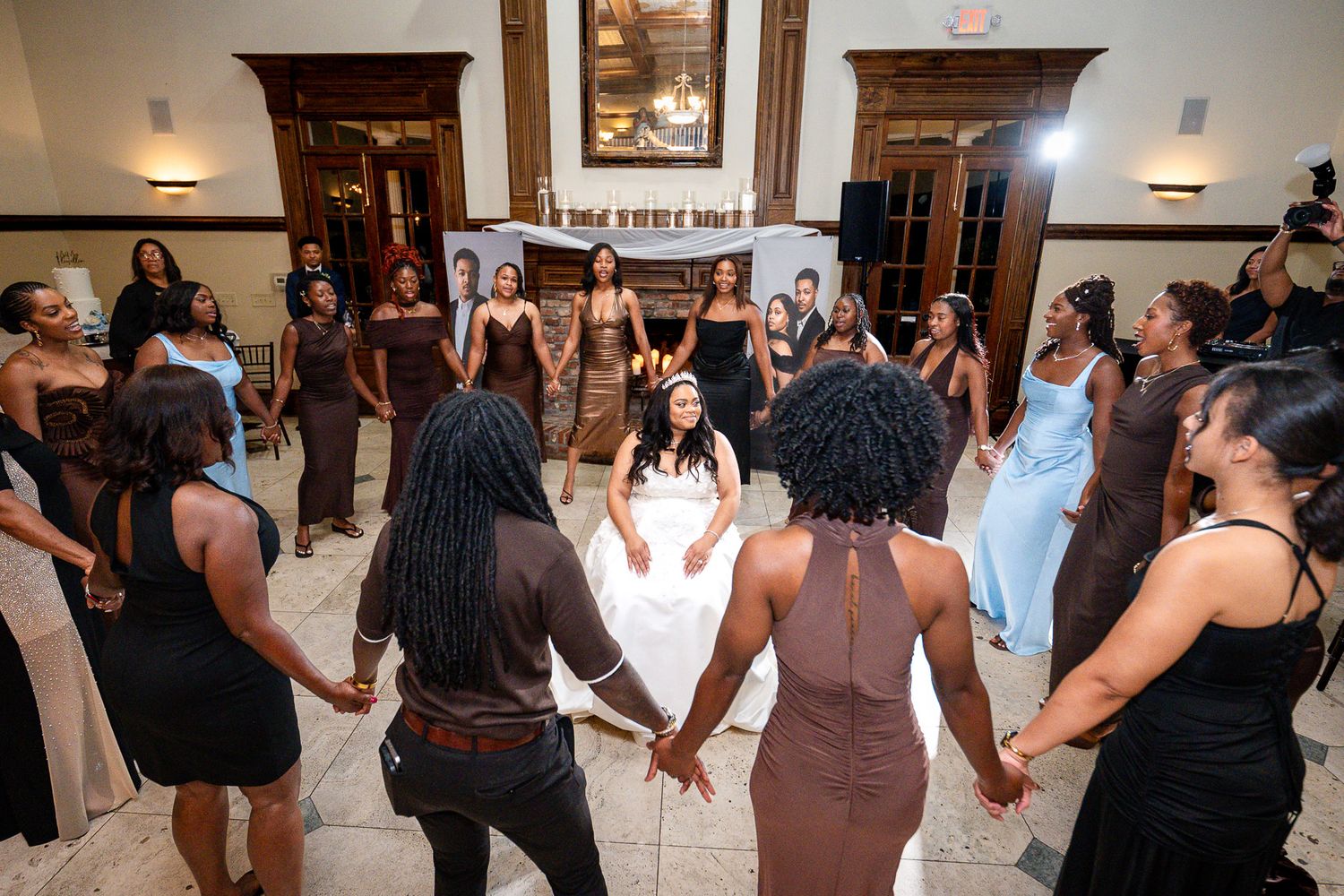 Bride in white gown surrounded by guests holding hands in a circle during a joyful wedding reception dance.