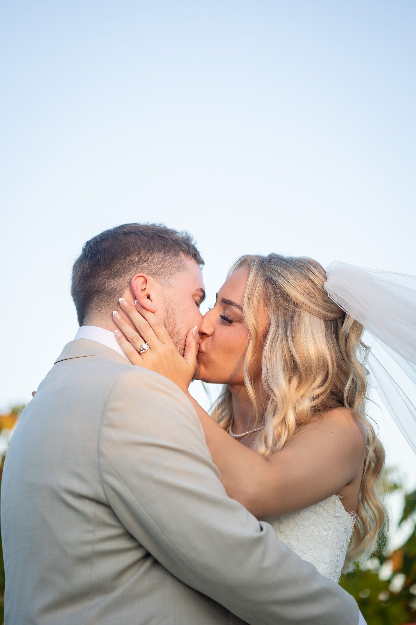 A series of four romantic wedding photos showing a couple sharing a kiss in a beige suit and white dress.