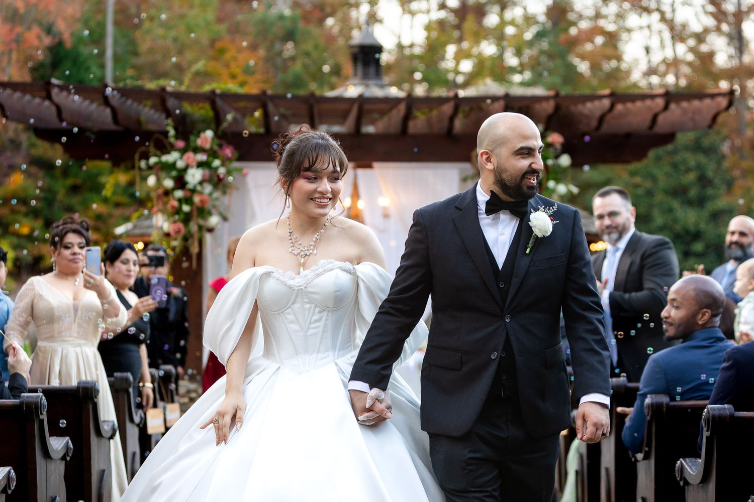 Bride and groom walk hand in hand down the aisle after their wedding ceremony at Rocky's Lake Estate