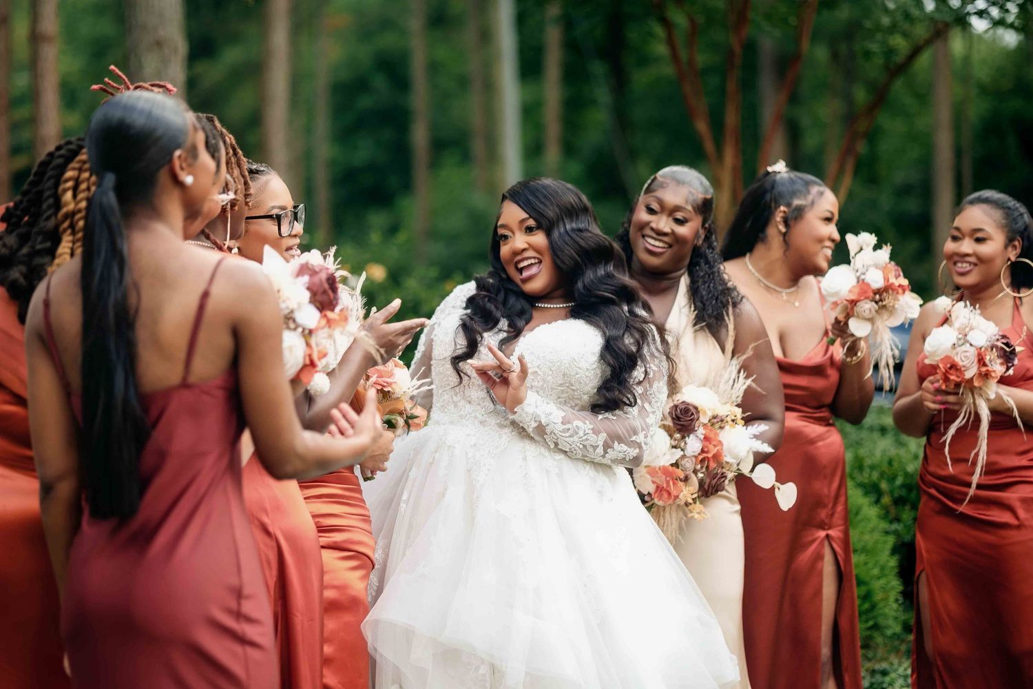 Bridal party wearing burgundy bridesmaid dresses laughing joyfully with bouquets at The Castle at Wildwood Gardens