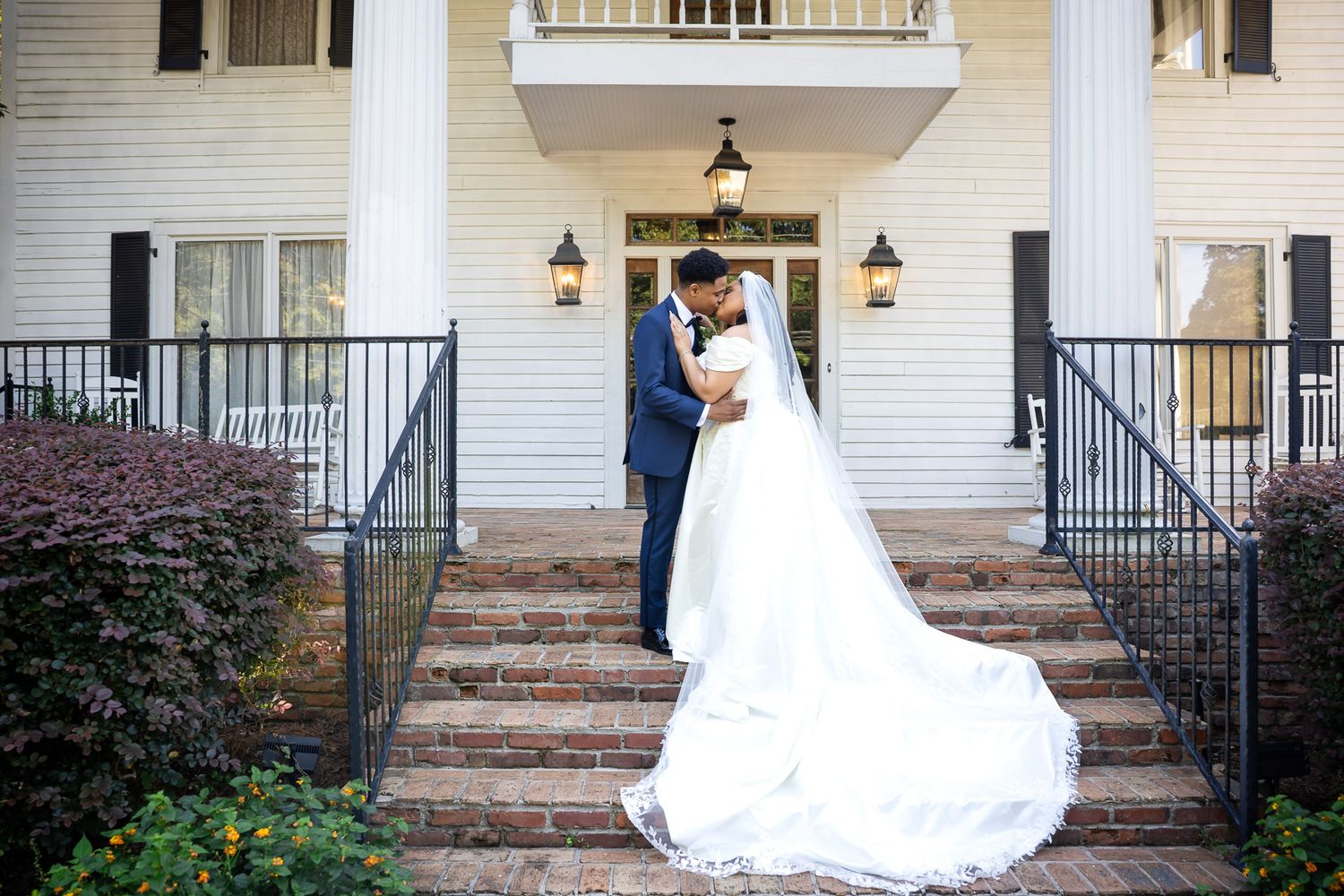 Bride and groom share a romantic embrace on brick steps outside Carl House wedding venue
