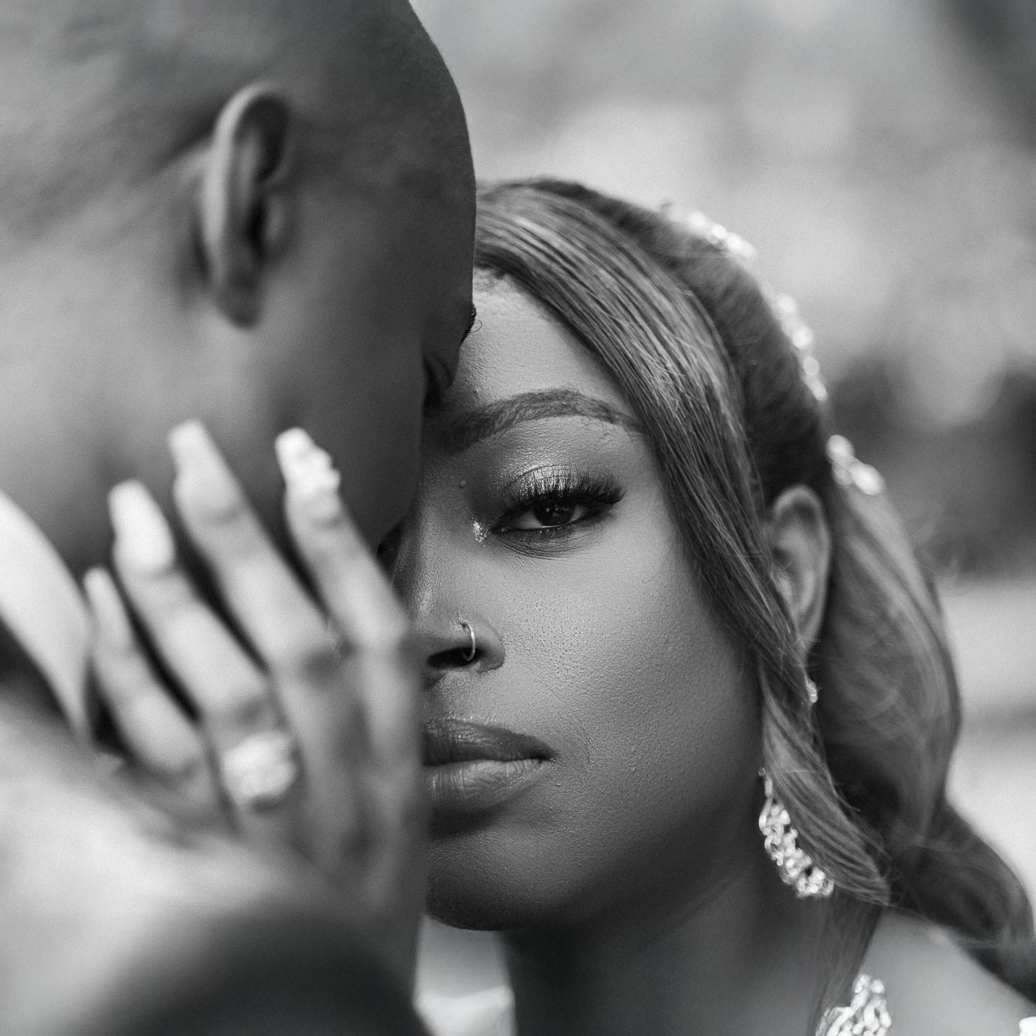 Intimate black and white close-up portrait of a couple sharing a tender moment with visible diamond earrings.