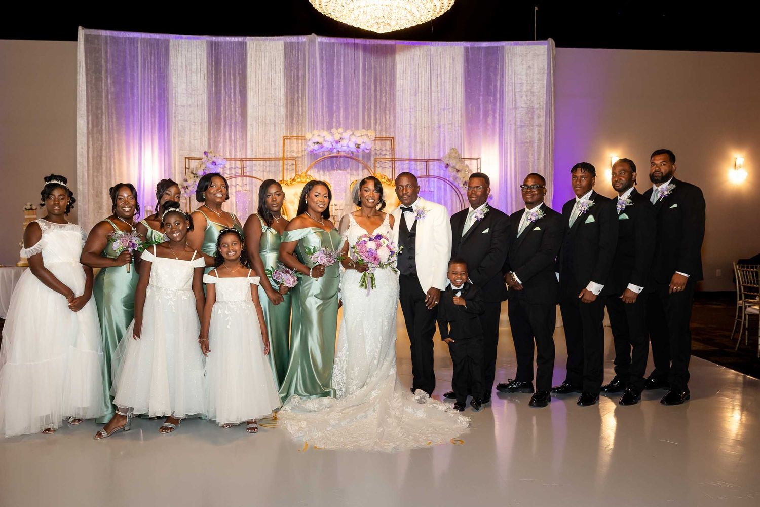 Wedding party poses together in venue with mint green bridesmaid dresses and black tuxedos.