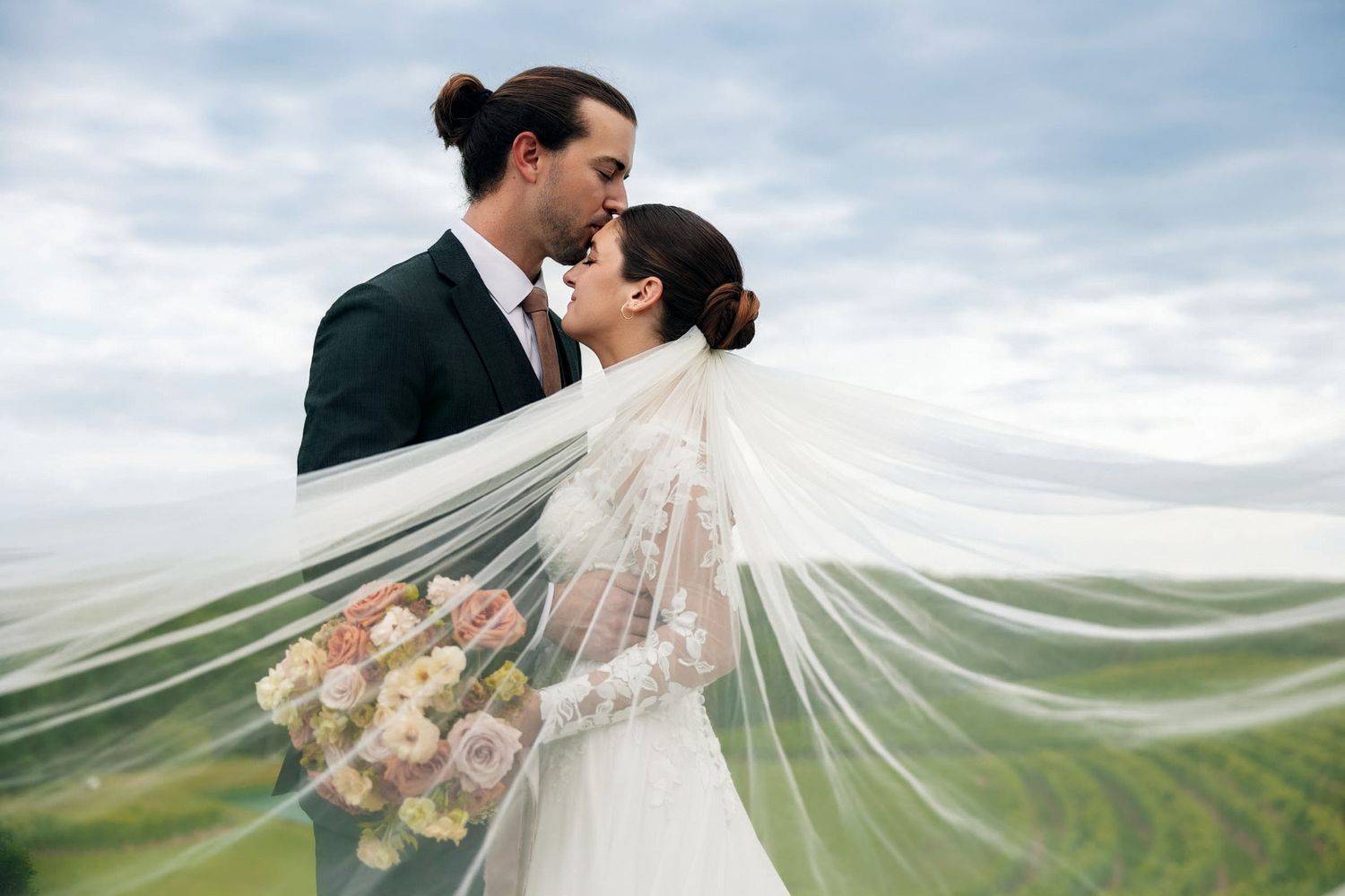 Bride and groom share a romantic kiss at their wedding at Montaluce Winery in Dahlonega, GA, against a vineyard backdrop.