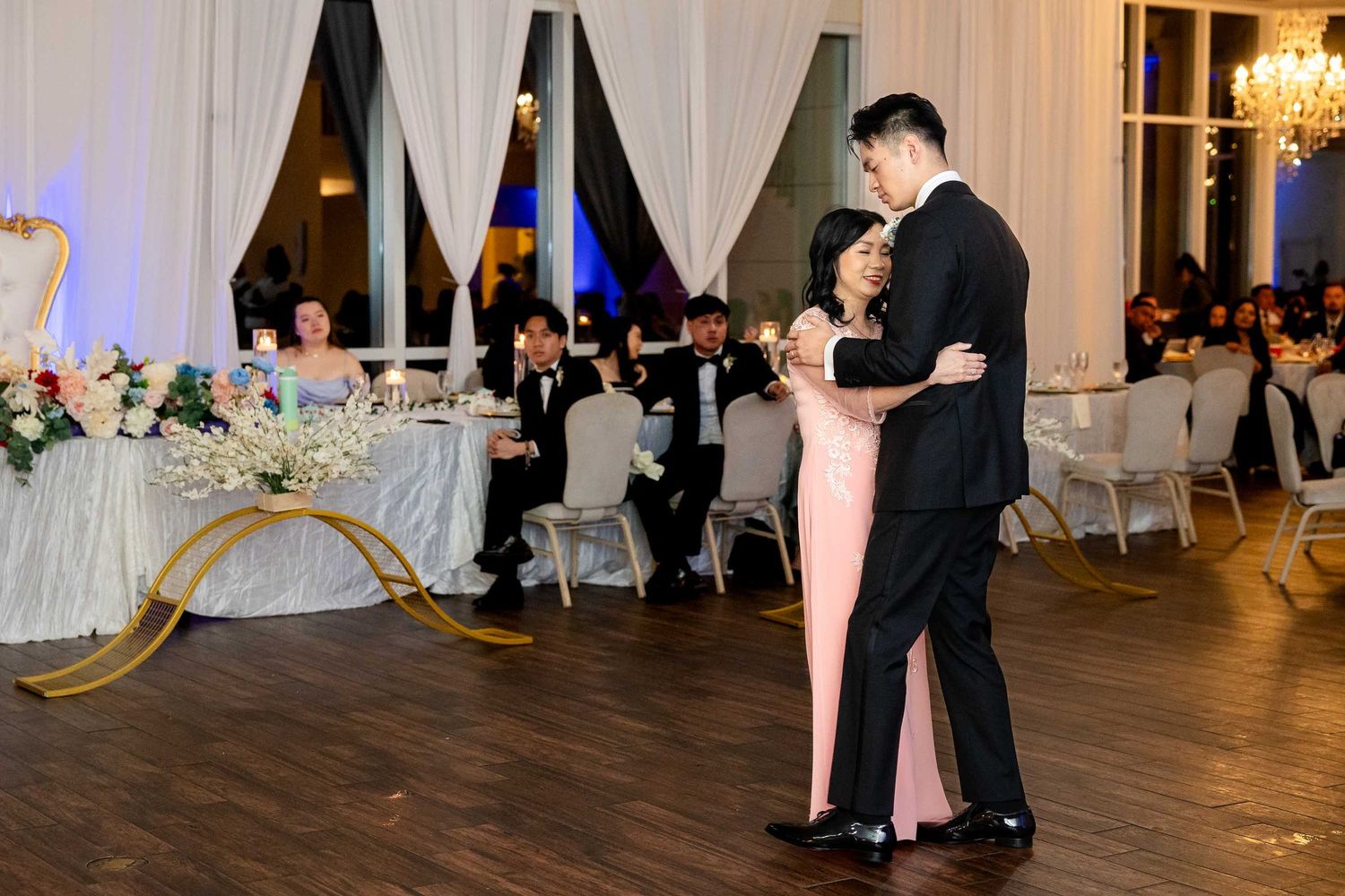 Couple shares elegant first dance at wedding reception with guests seated in background.