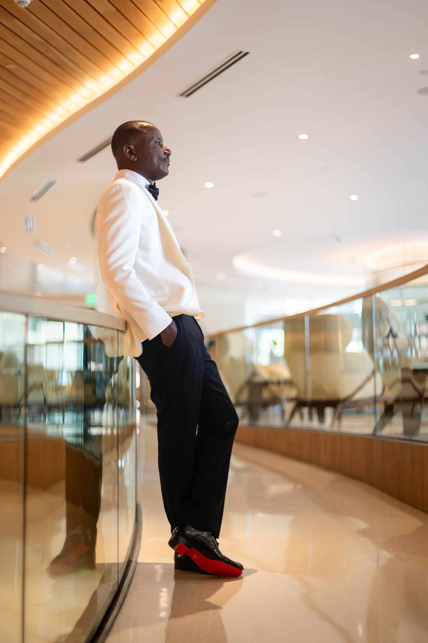 Stylish man in white tuxedo jacket standing in upscale venue interior.