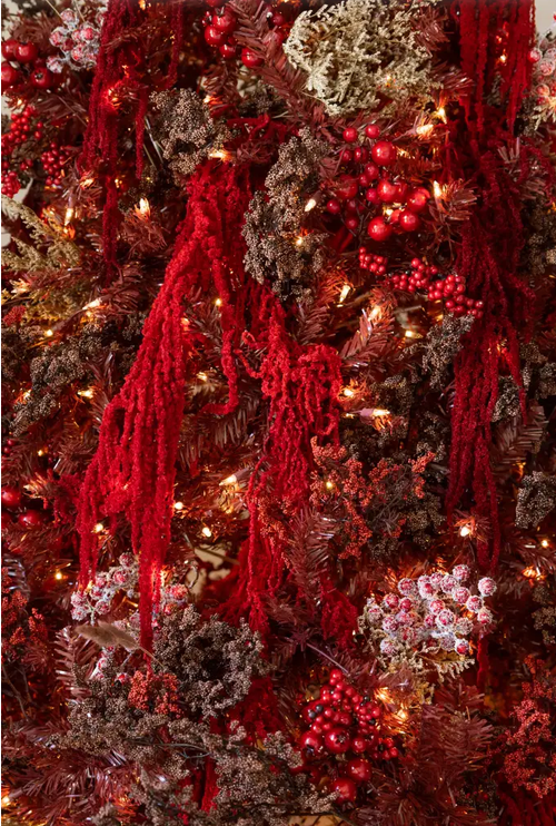 Lush Christmas tree decorated with red berry clusters, chenille tassels, warm fairy lights, and frosted pine branches.