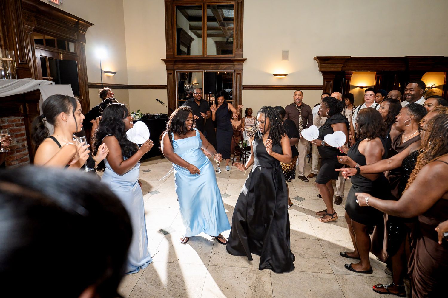 Guests dancing and celebrating at an elegant wedding reception in a grand venue with warm lighting.