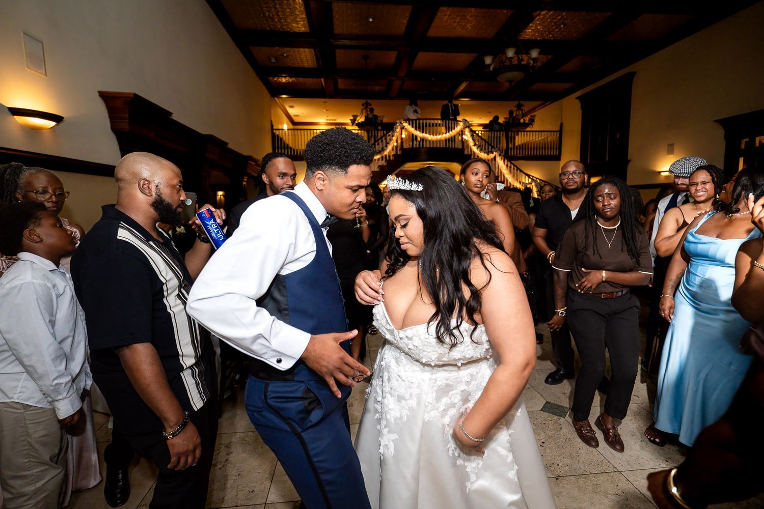 Bride and groom share first dance at wedding reception surrounded by guests in elegant venue.