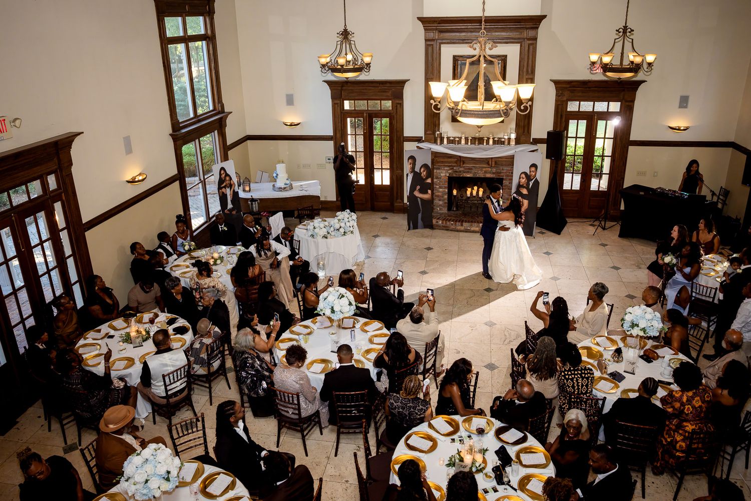 Elegant wedding reception in a grand ballroom with couple sharing first dance surrounded by guests at round tables.