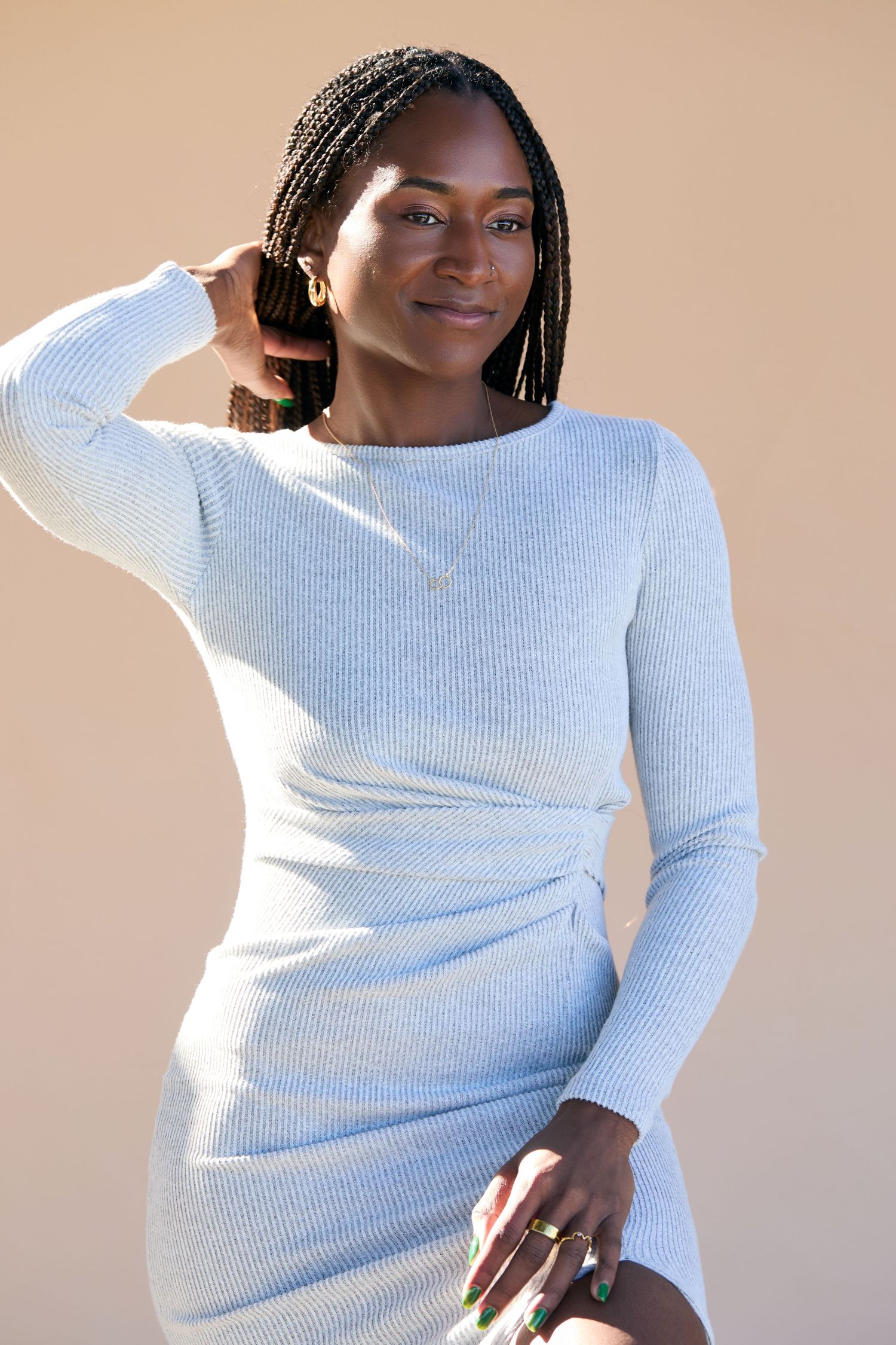 Woman in white ribbed sweater poses against neutral background showing different angles and expressions.