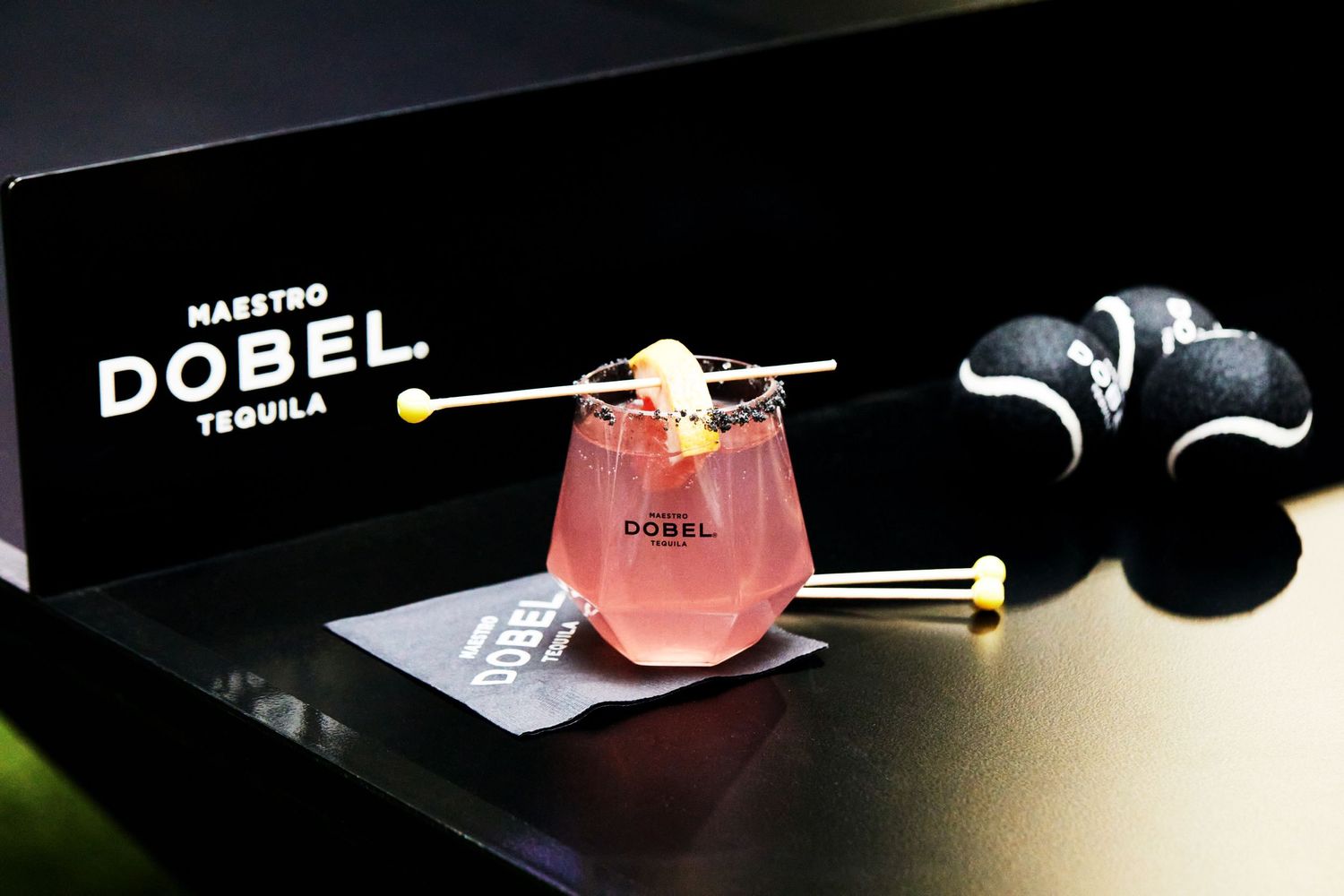 Pink DOBEL tequila cocktail served with garnish against dark background.