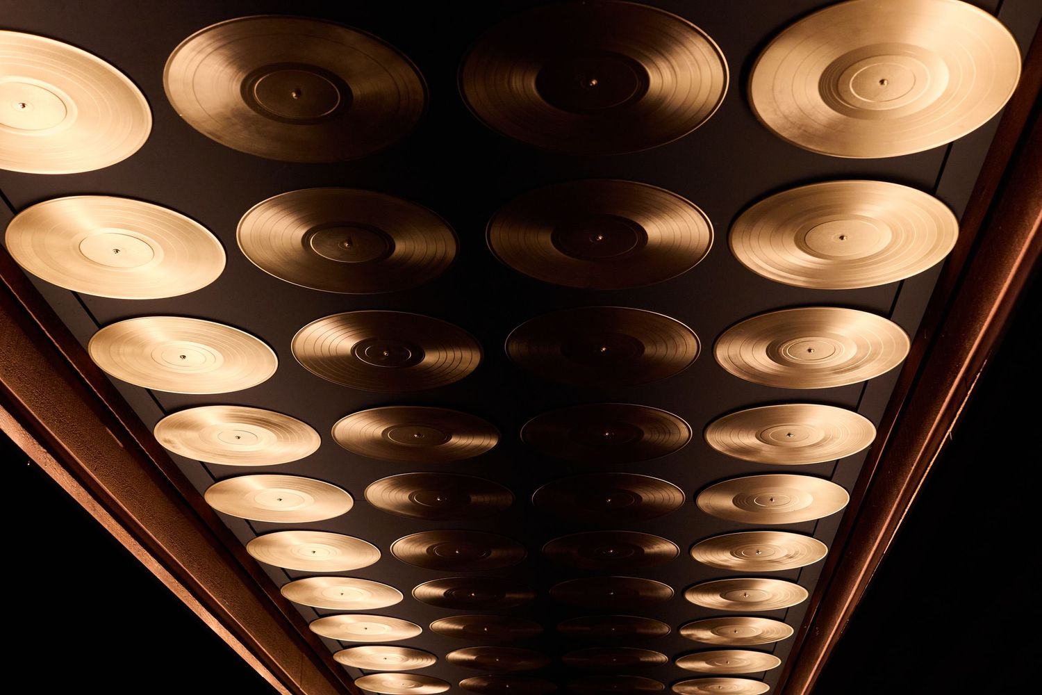 Repetitive pattern of circular ceiling lights creating a dramatic vanishing point perspective in a dark corridor.