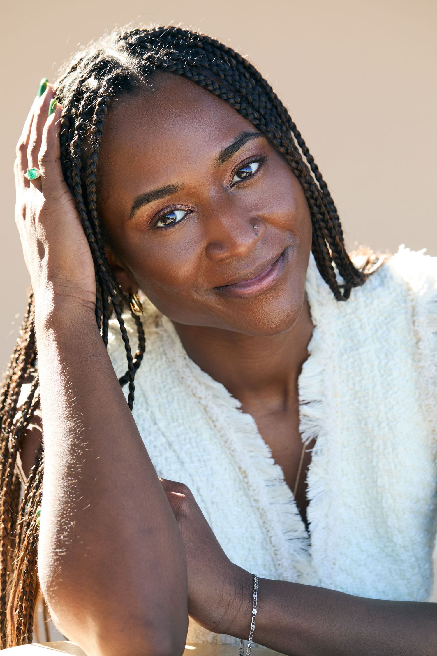 Close-up portraits with braided hair and white top showing warm expressions against a beige wall.