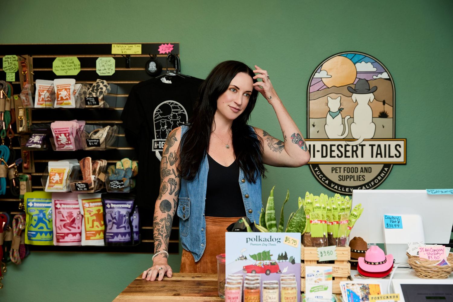 Inside a pet store with green walls displaying various treats and supplies on wooden shelving.